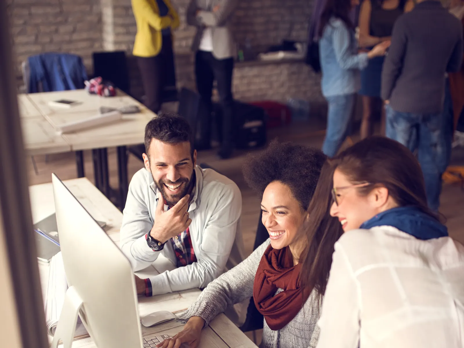 a group of people sitting at a table looking at a laptop