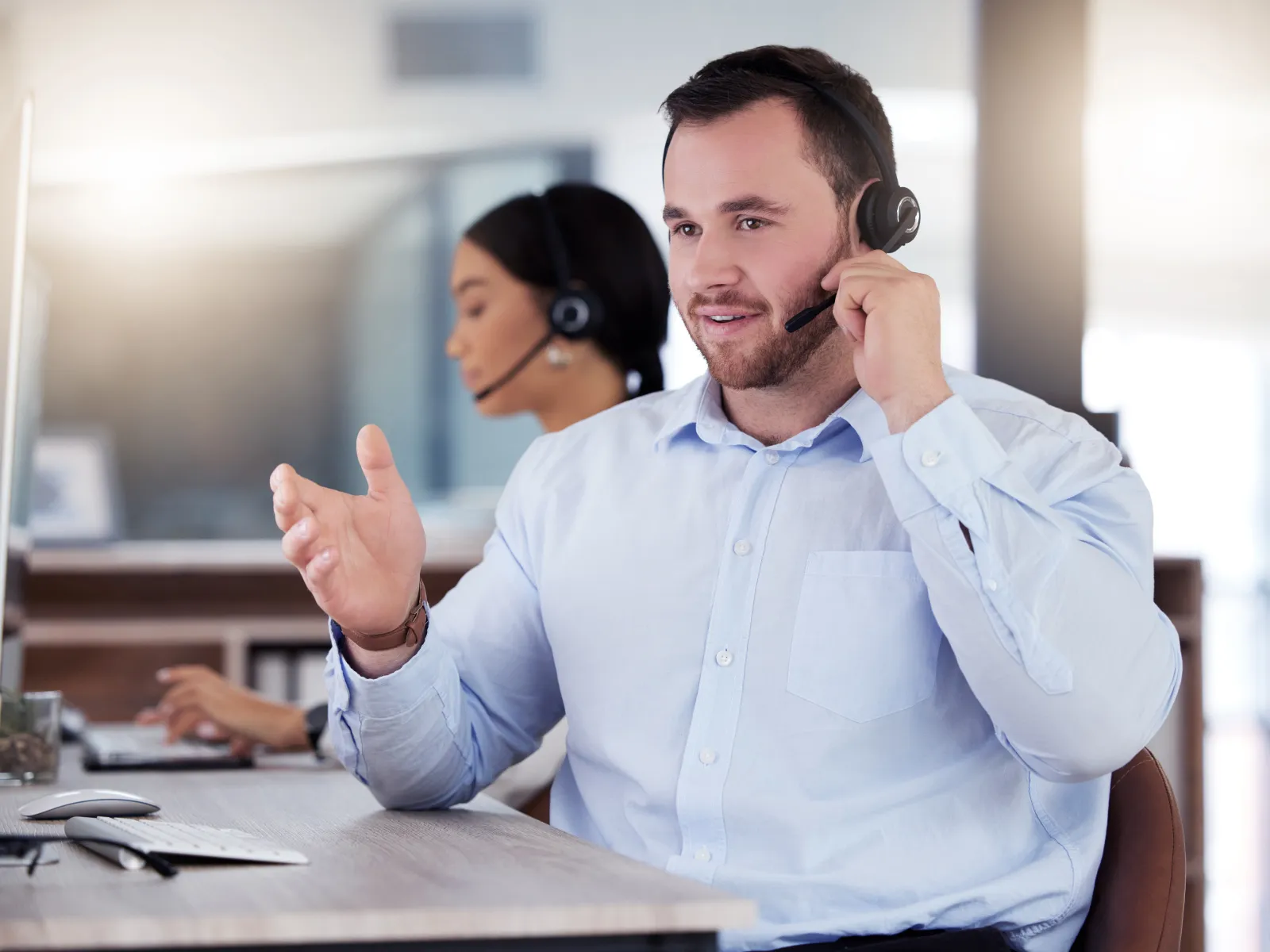 Customer service agents wearing headsets working at computers in a modern office environment