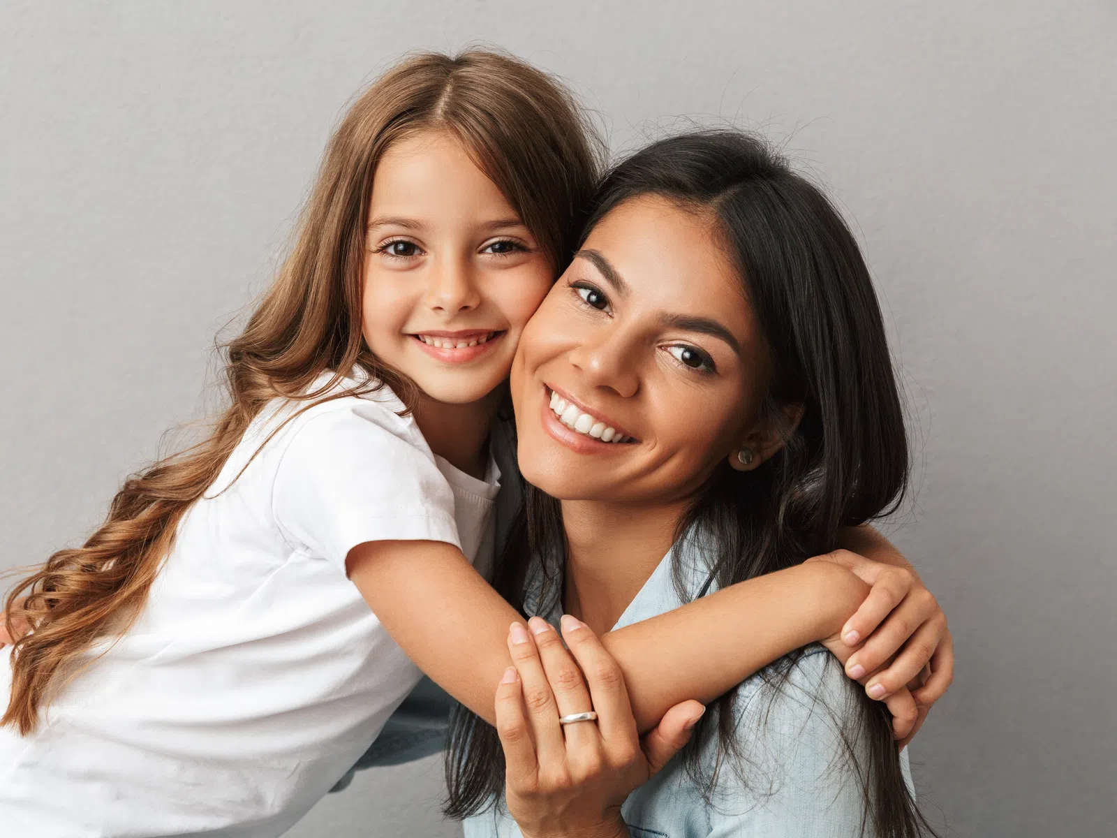 Smiling mother and daughter hugging each other, showing warm family love and close bond.