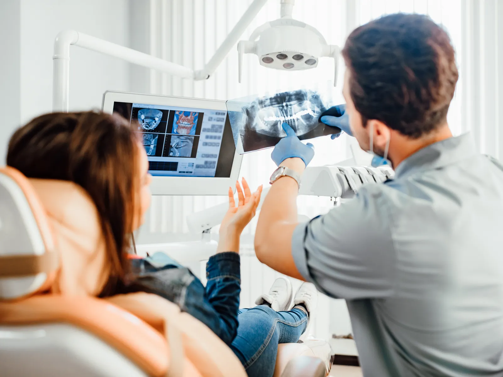 Dentist reviewing dental X-ray with patient in modern dental clinic, discussing oral health and treatment.