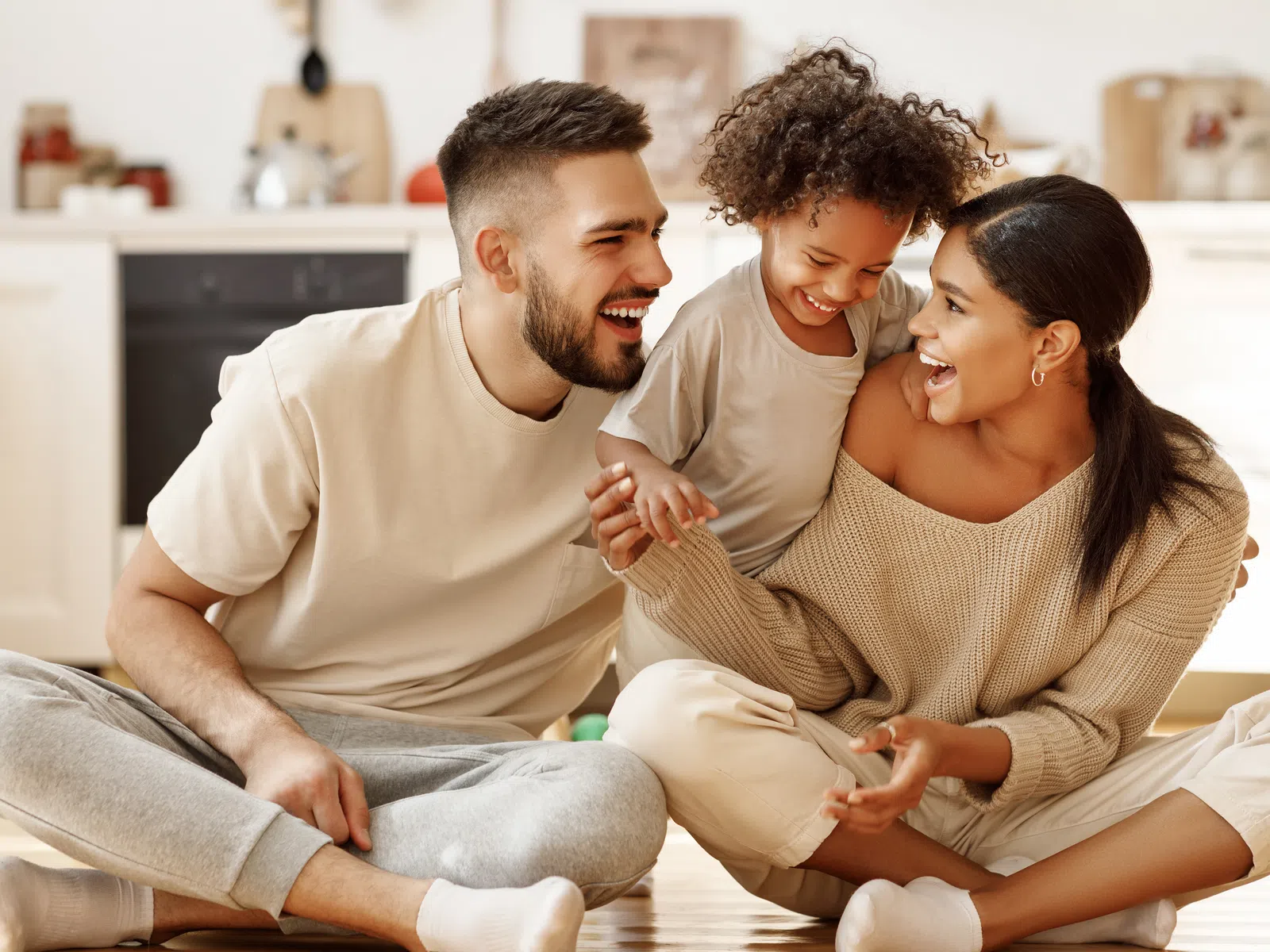 Happy multicultural family sitting on the floor, laughing and enjoying time together in a cozy home setting
