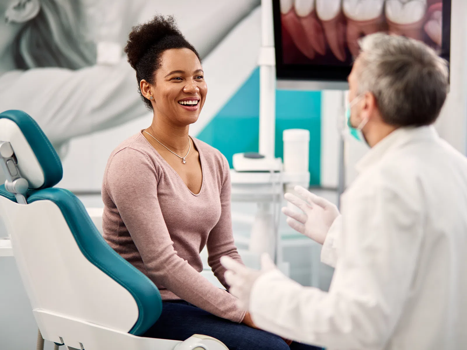 Smiling woman sitting in dental chair talking with dentist in modern dental office