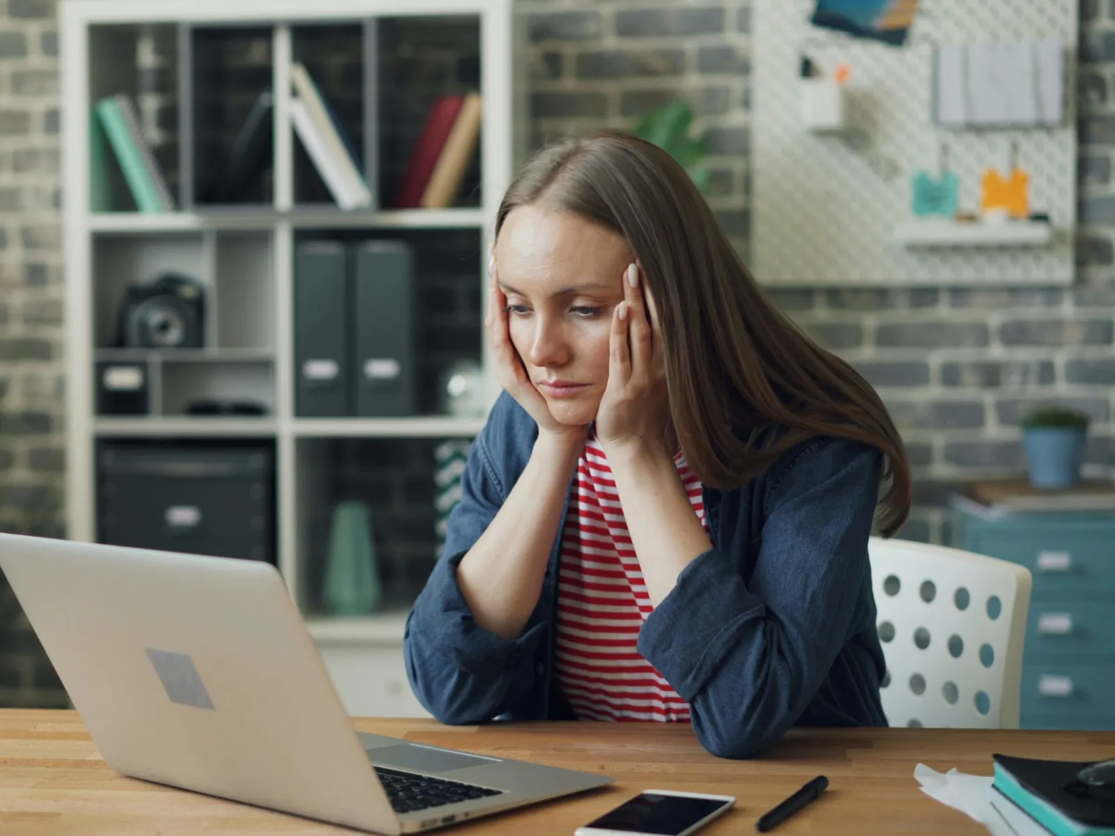 a woman sitting at a table with her hand on her face