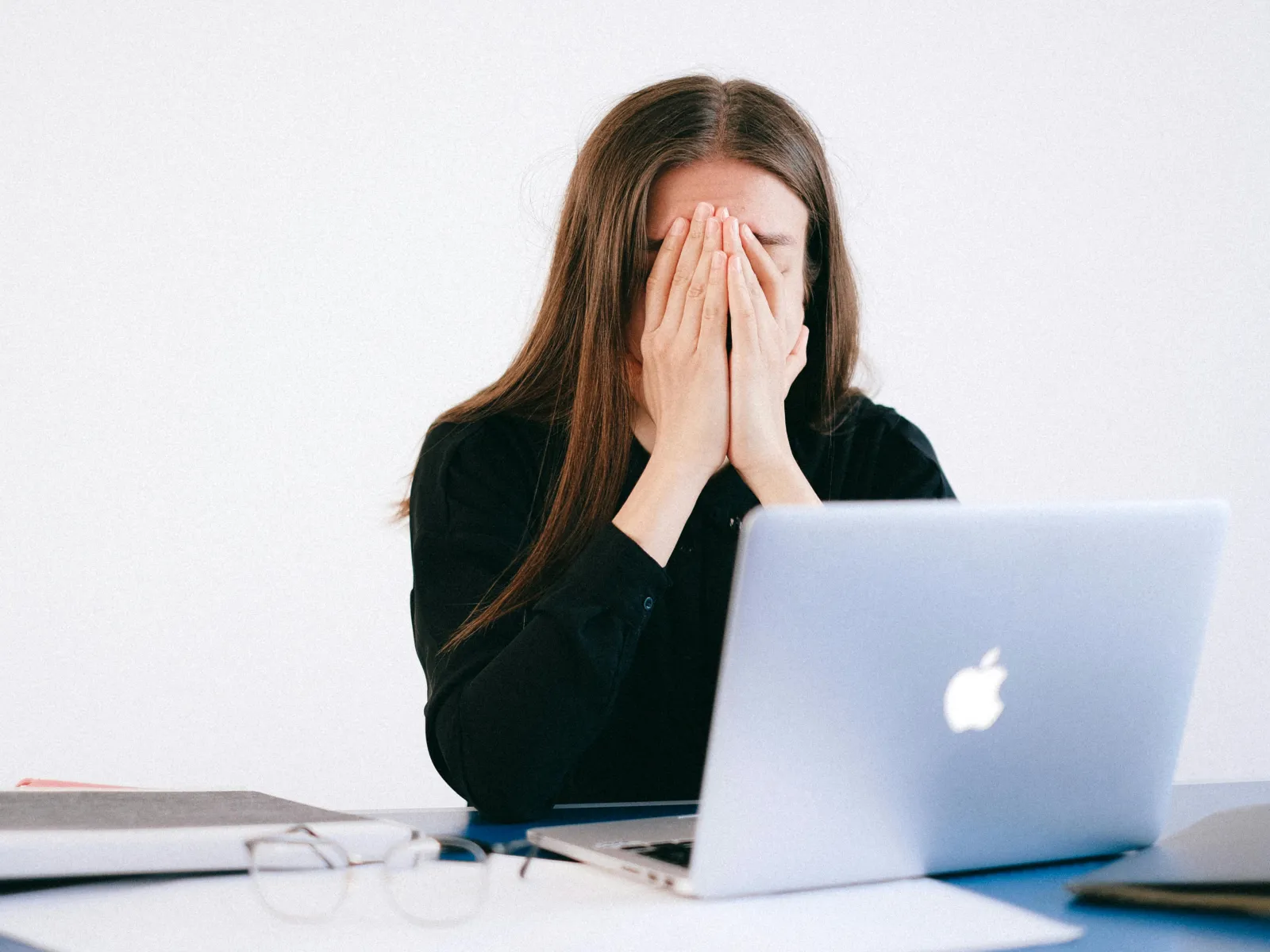 a woman with her hands on her face looking at a laptop