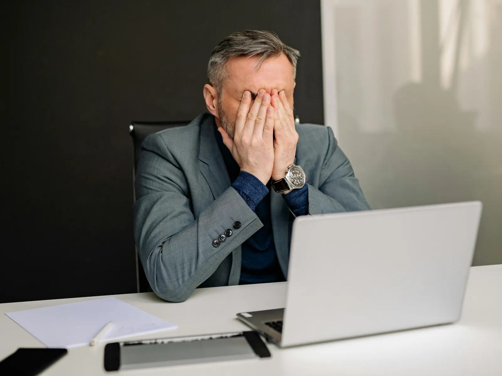 a man sitting at a desk with his hand on his face