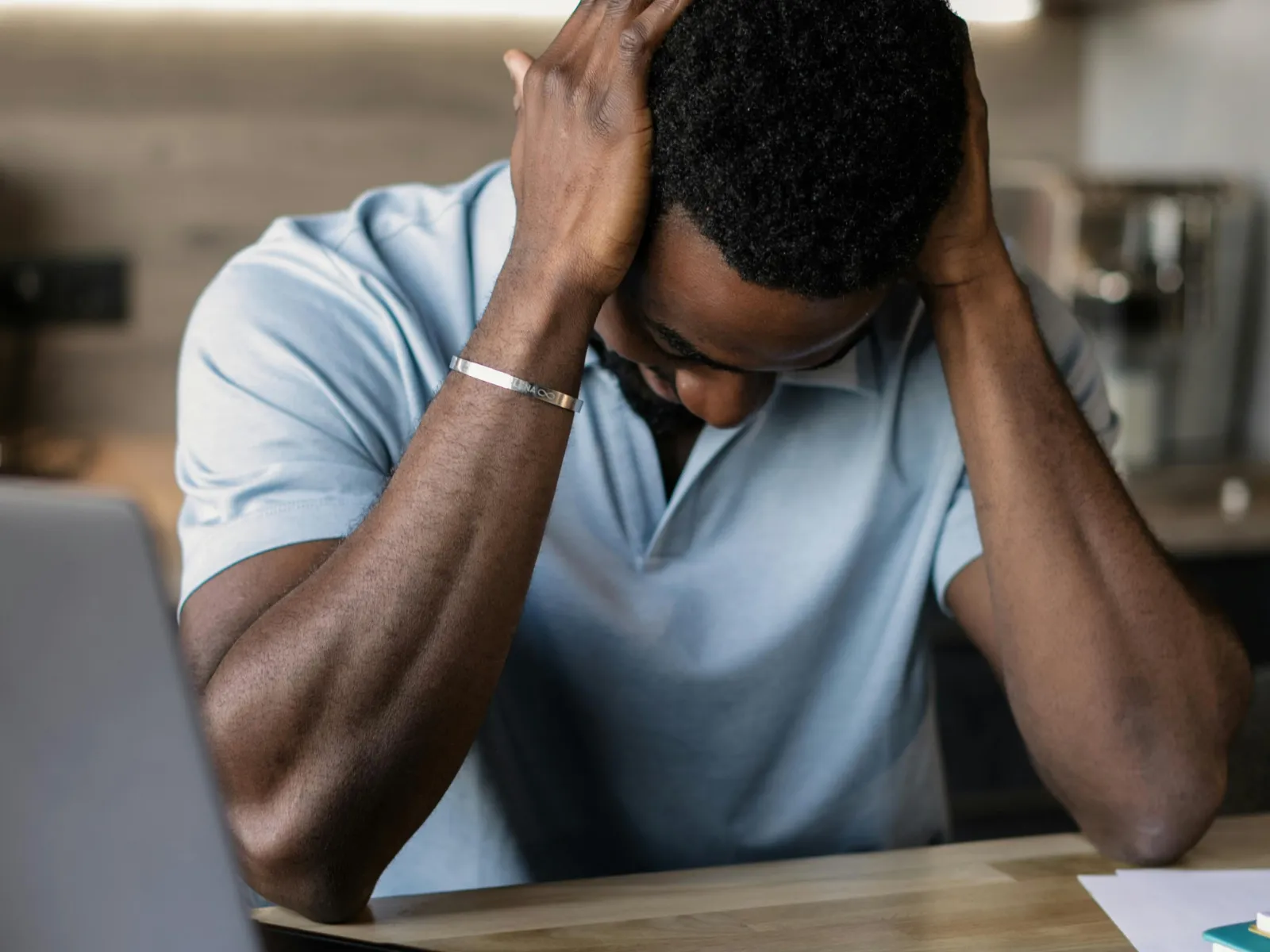 a man with his head in his hands looking at a laptop