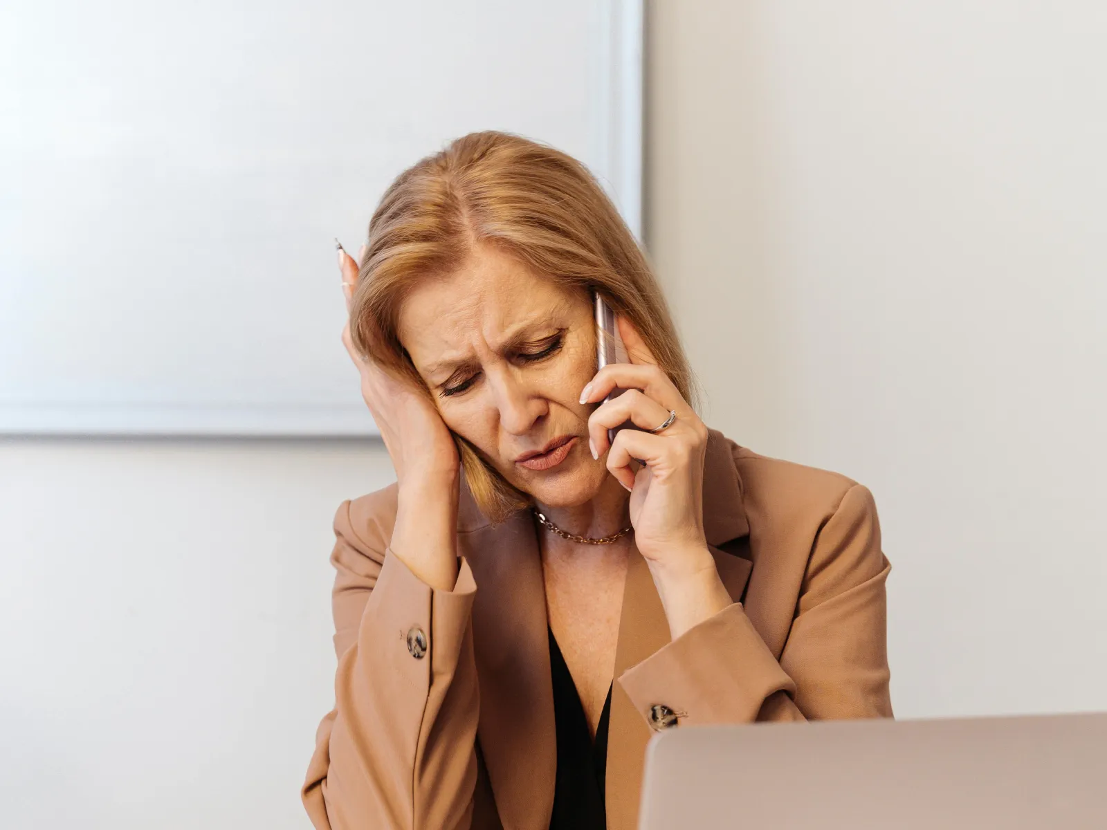 a woman sitting at a desk with her hand on her face