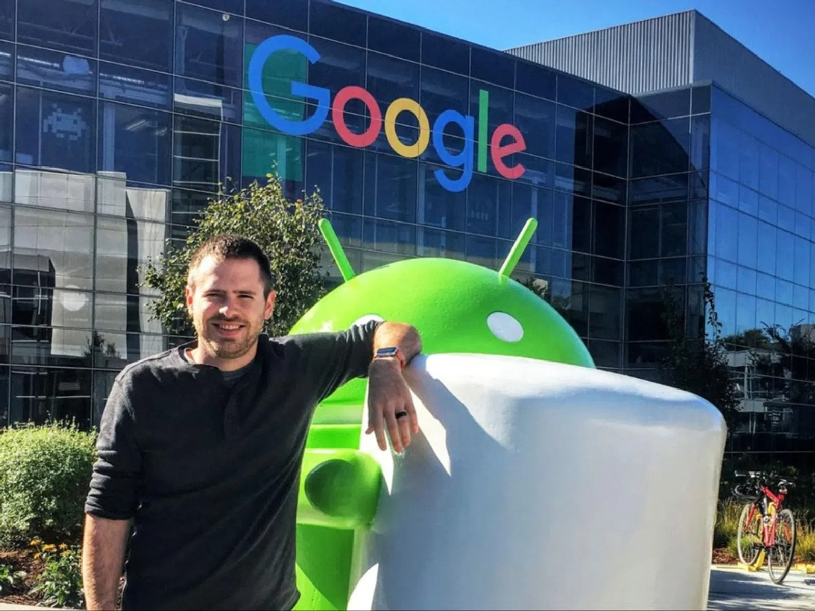 Jeff Jahn leaning on large Android Marshmallow statue outside Google building with logo on glass facade