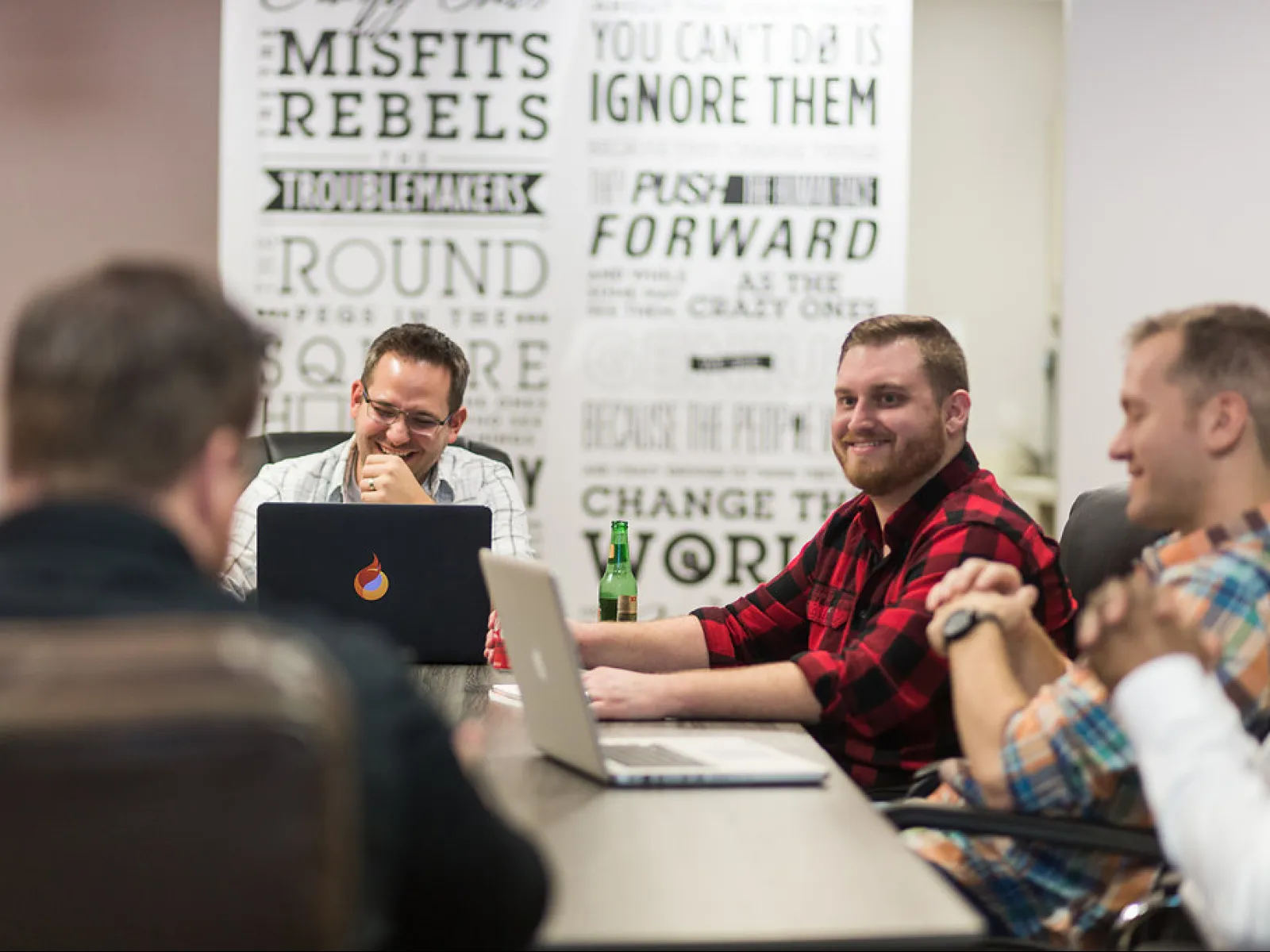a group of men sitting at a table with laptops