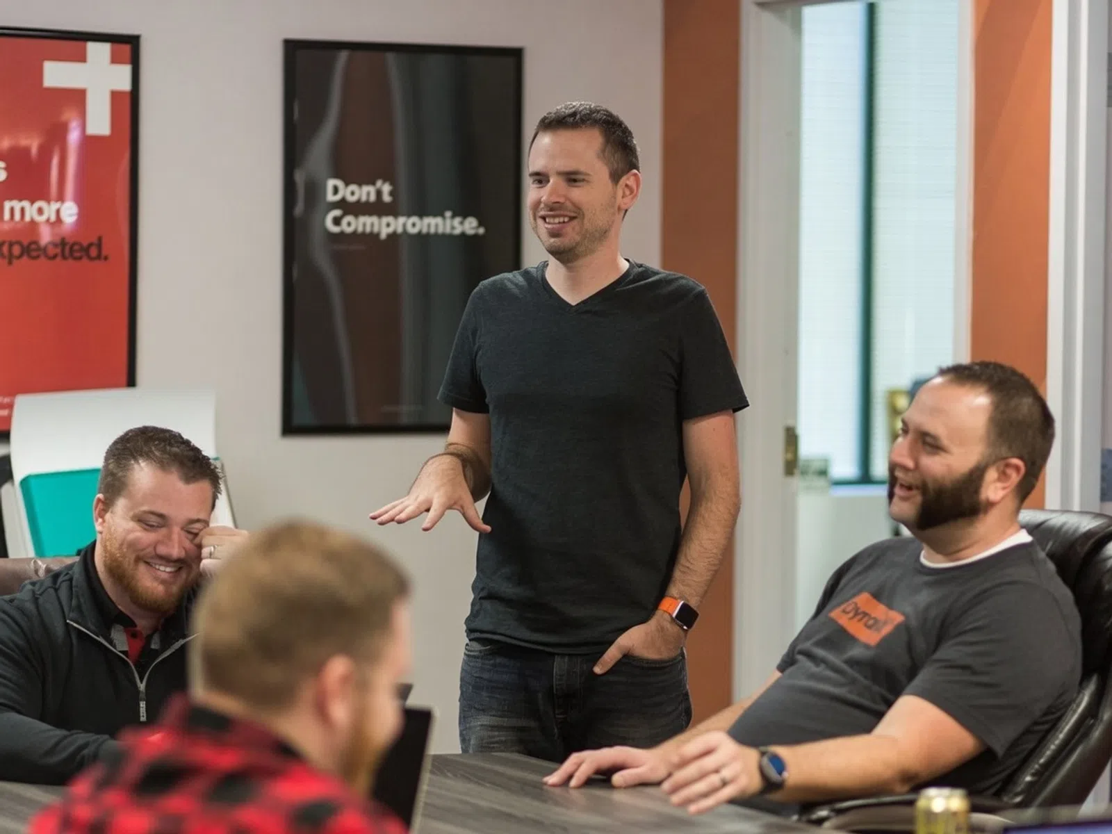 Group of men having a lively discussion in a modern office with motivational posters on the wall