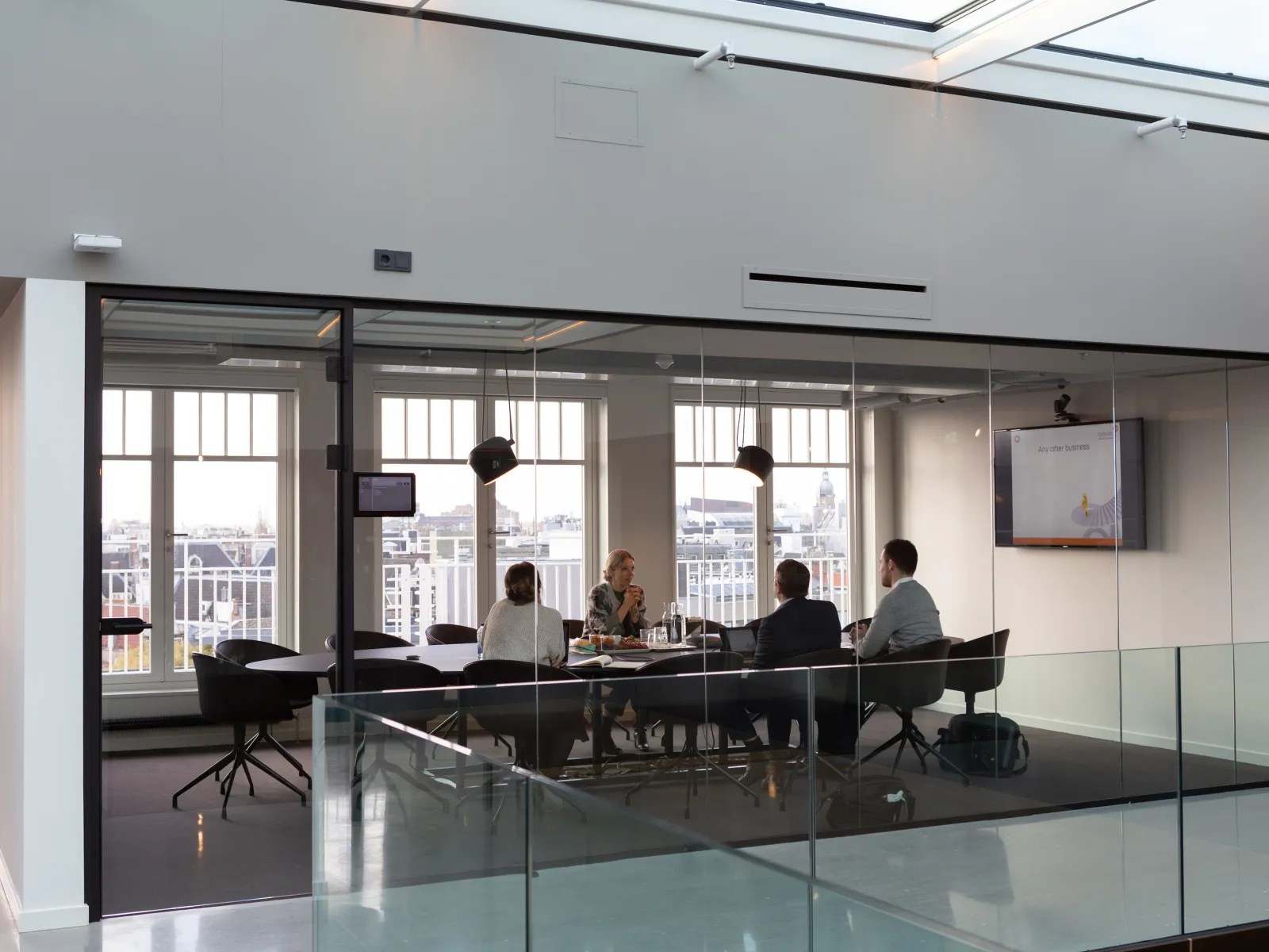 a group of people sitting around a table in a room with windows