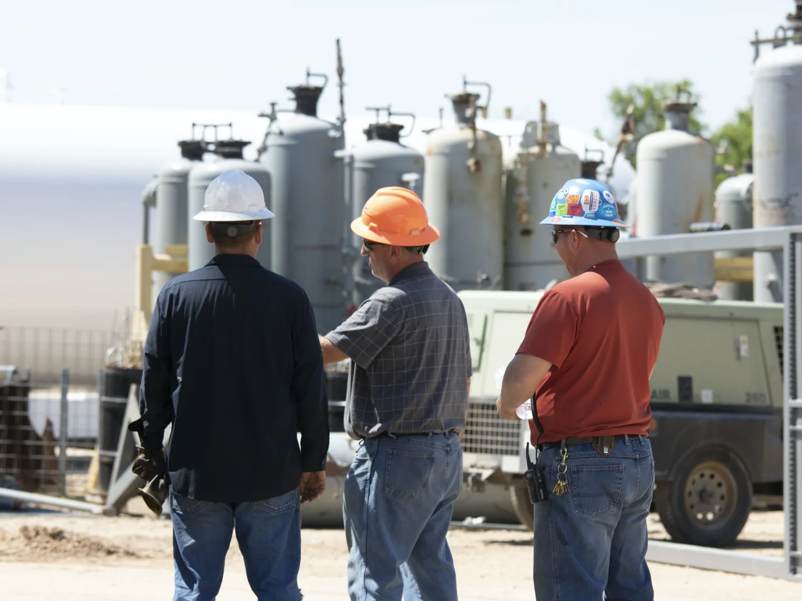 a group of workers with prevailing wages wearing hardhats and standing in front of a factory