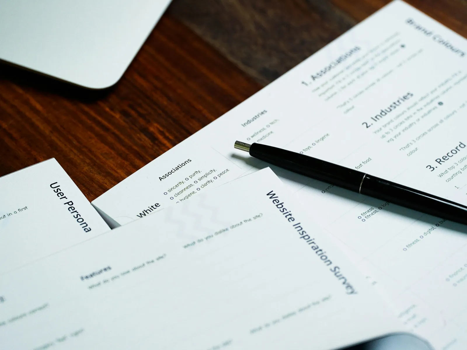 Work desk with survey forms and a pen for website inspiration and user persona development.