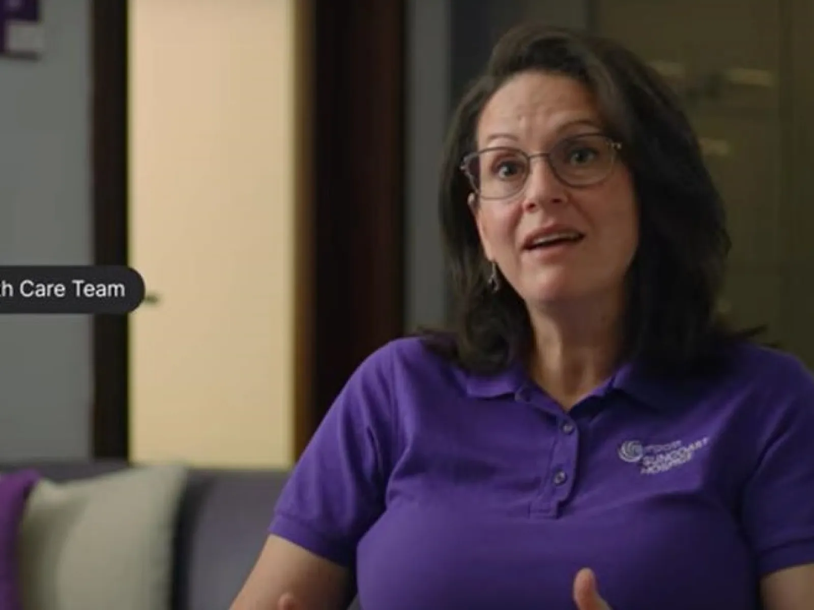 Woman in purple Empath Care Team polo shirt speaking with text messages displayed on screen