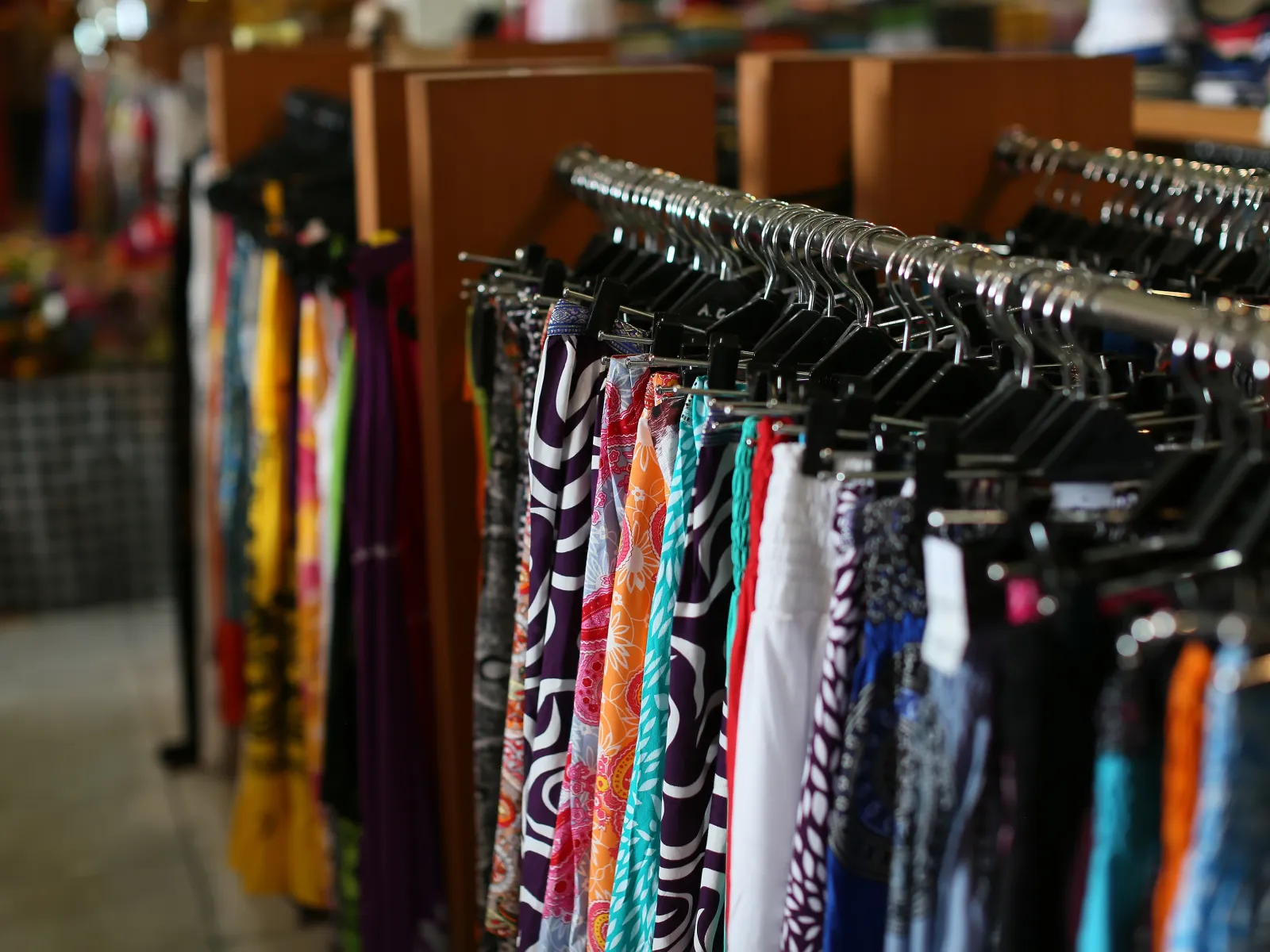 Colorful patterned skirts hanging on racks inside a clothing store with blurred background.