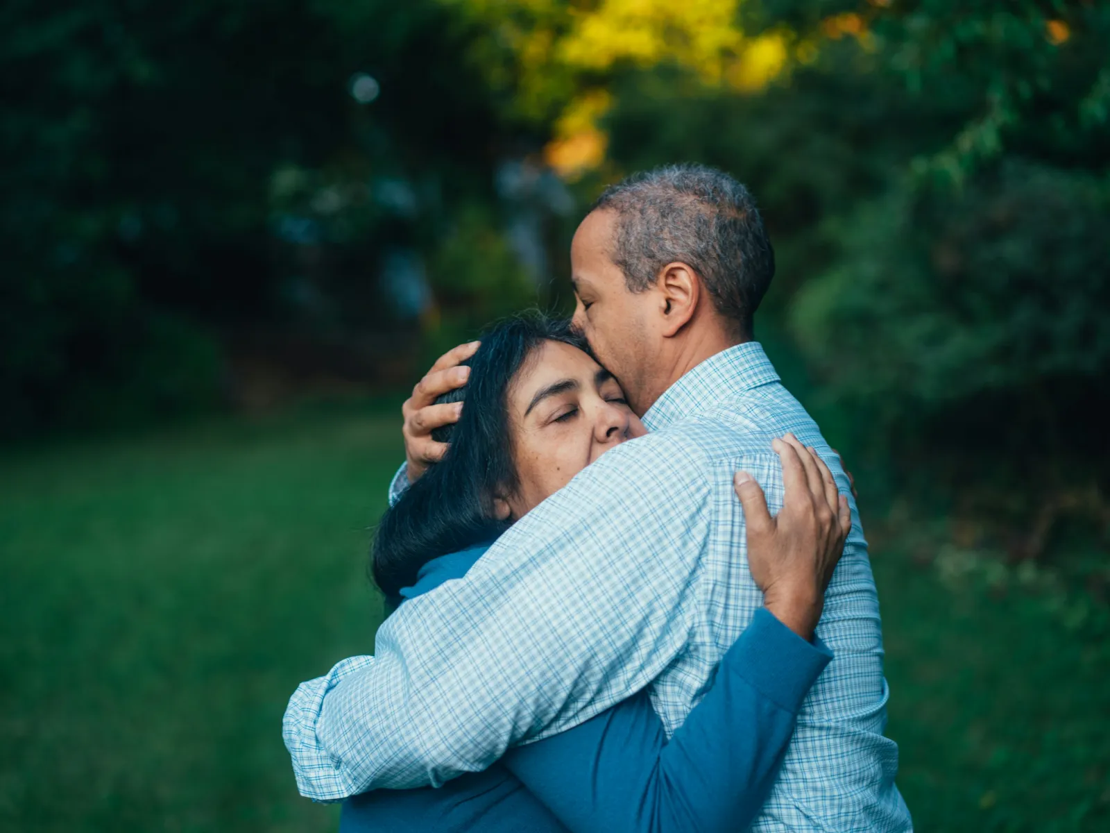 Middle-aged couple embracing outdoors in a green park with affection and comfort on a sunny day
