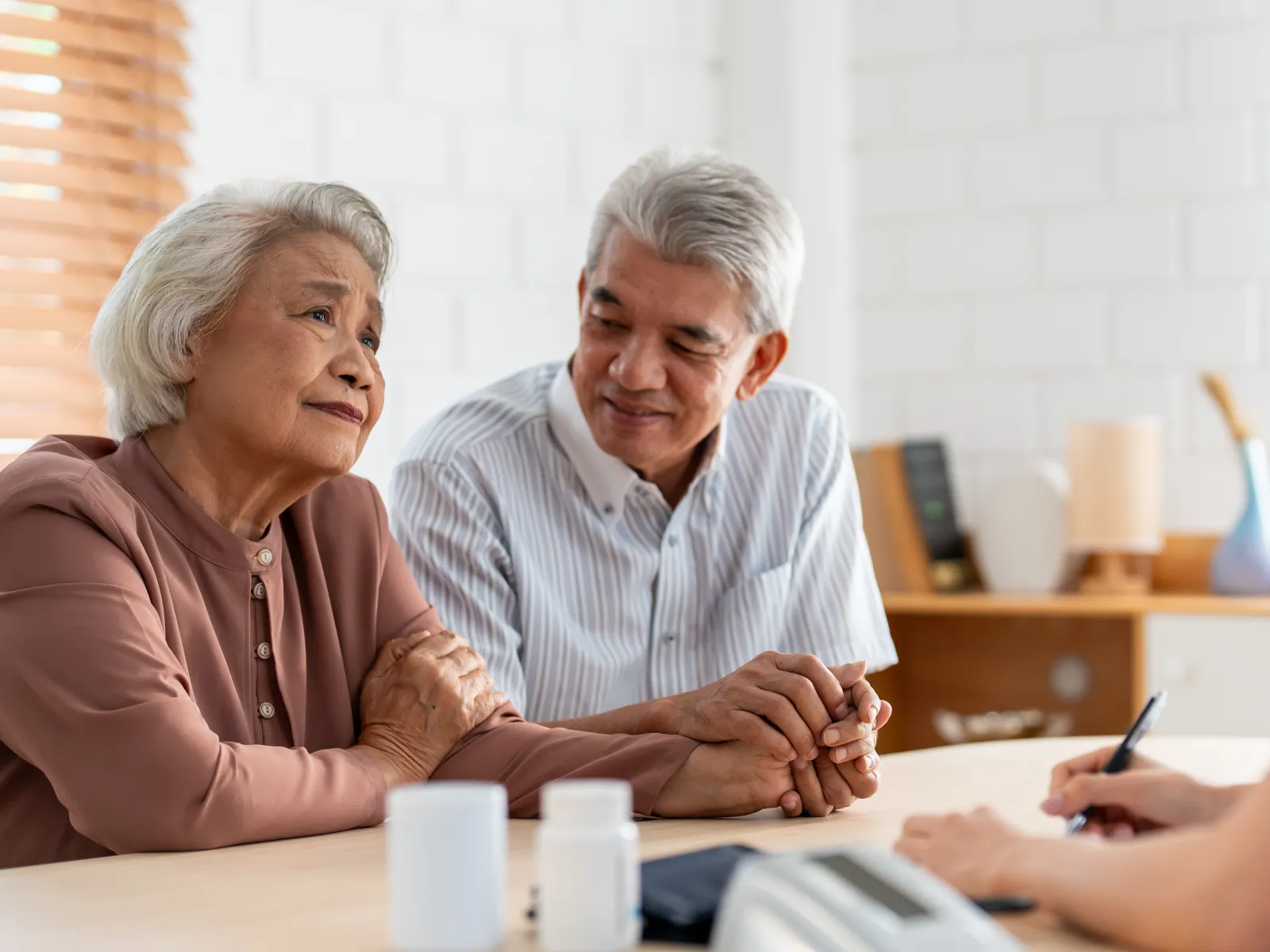 Senior couple consulting with a healthcare professional in a warm, bright clinic setting.