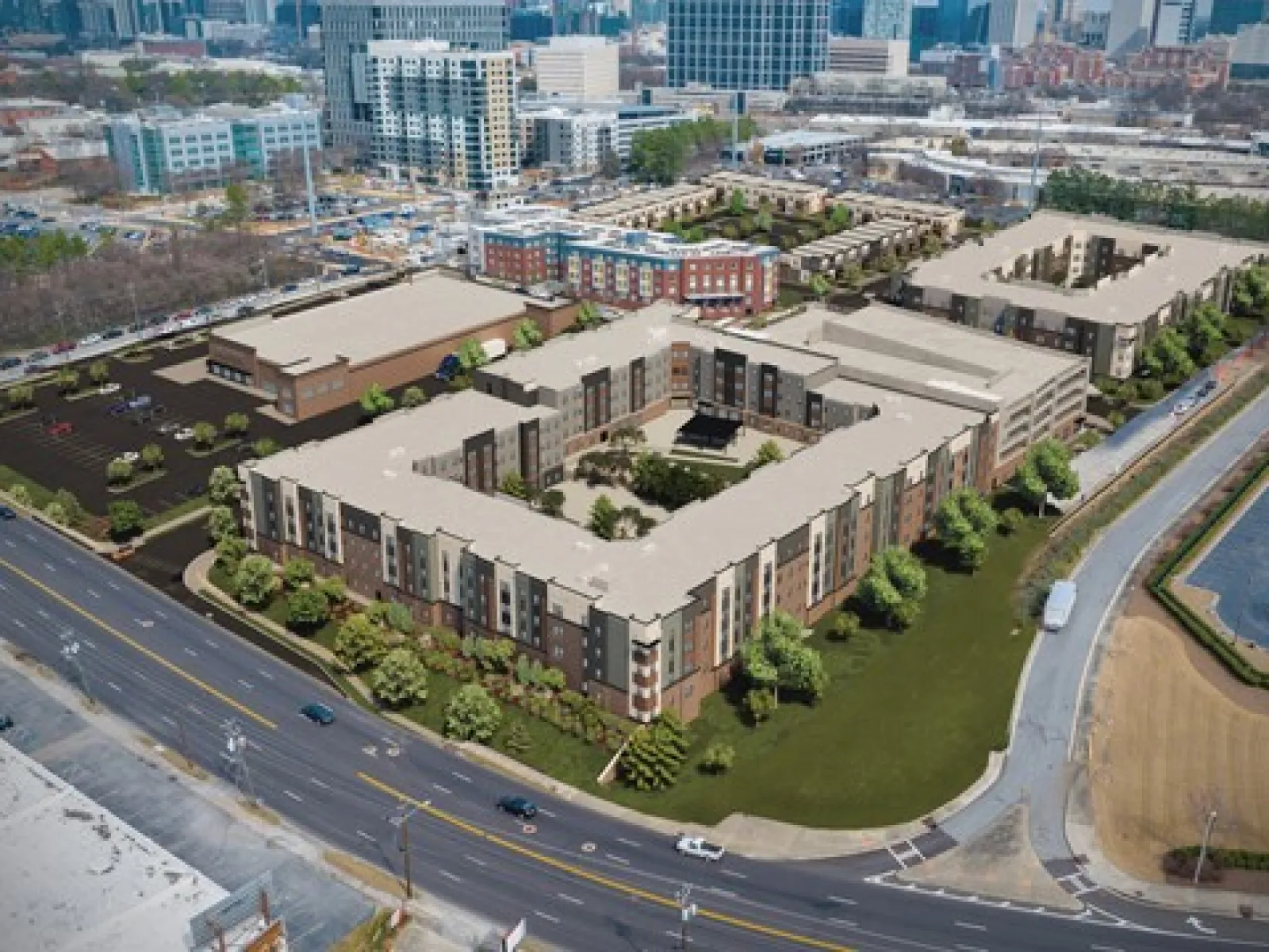 Aerial view of large modern apartment complex with central courtyards near busy city streets and surrounding buildings.