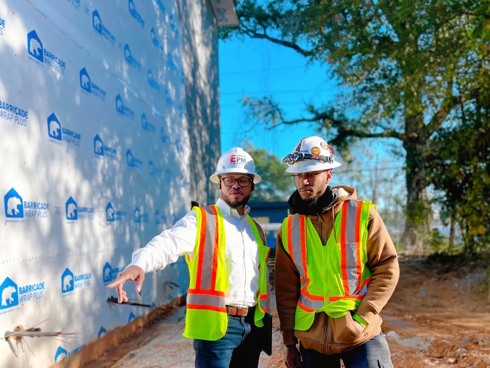 men wearing safety vests and reflectors standing next to a wall