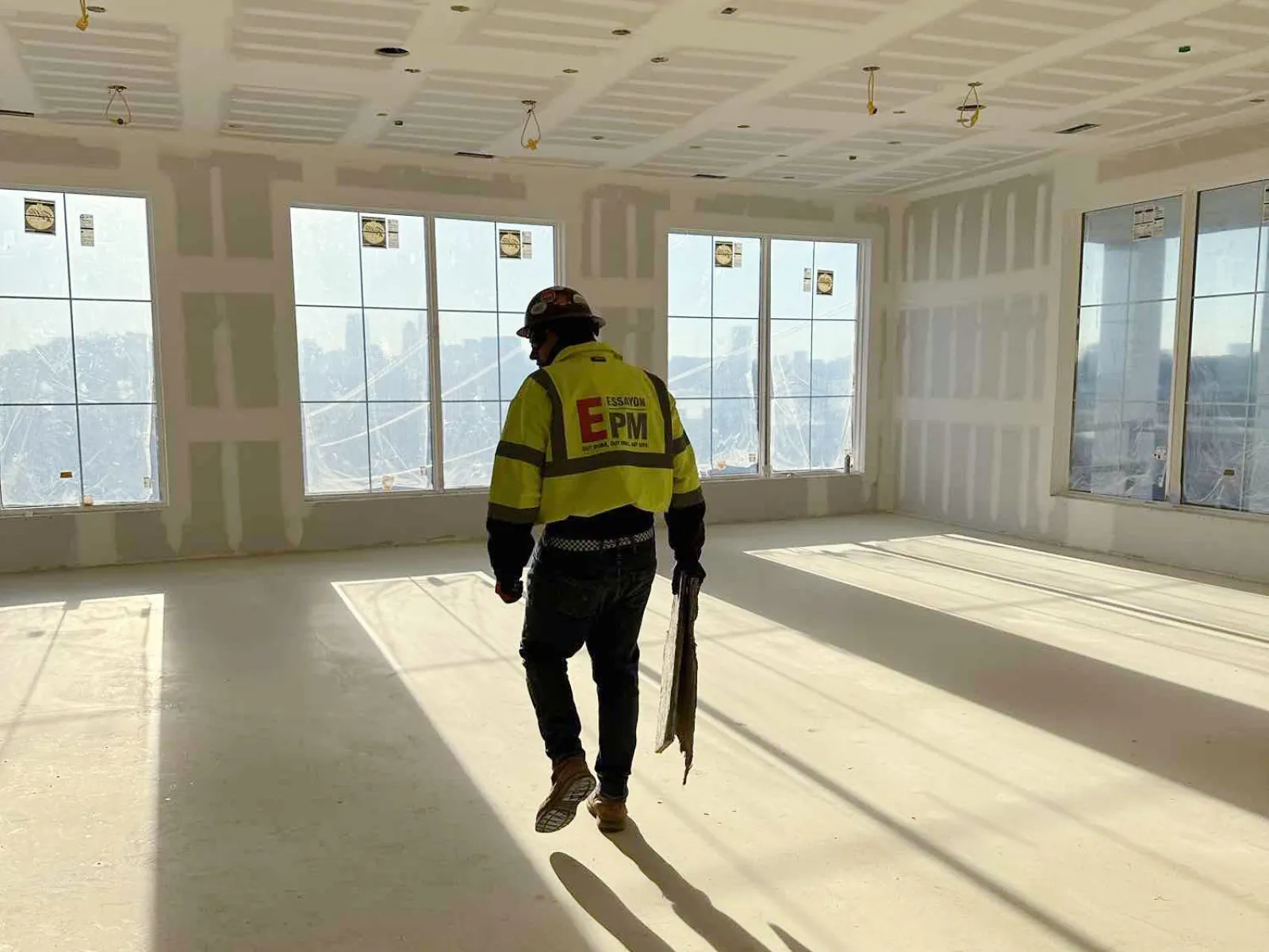 a man in a yellow vest walking in a large empty room