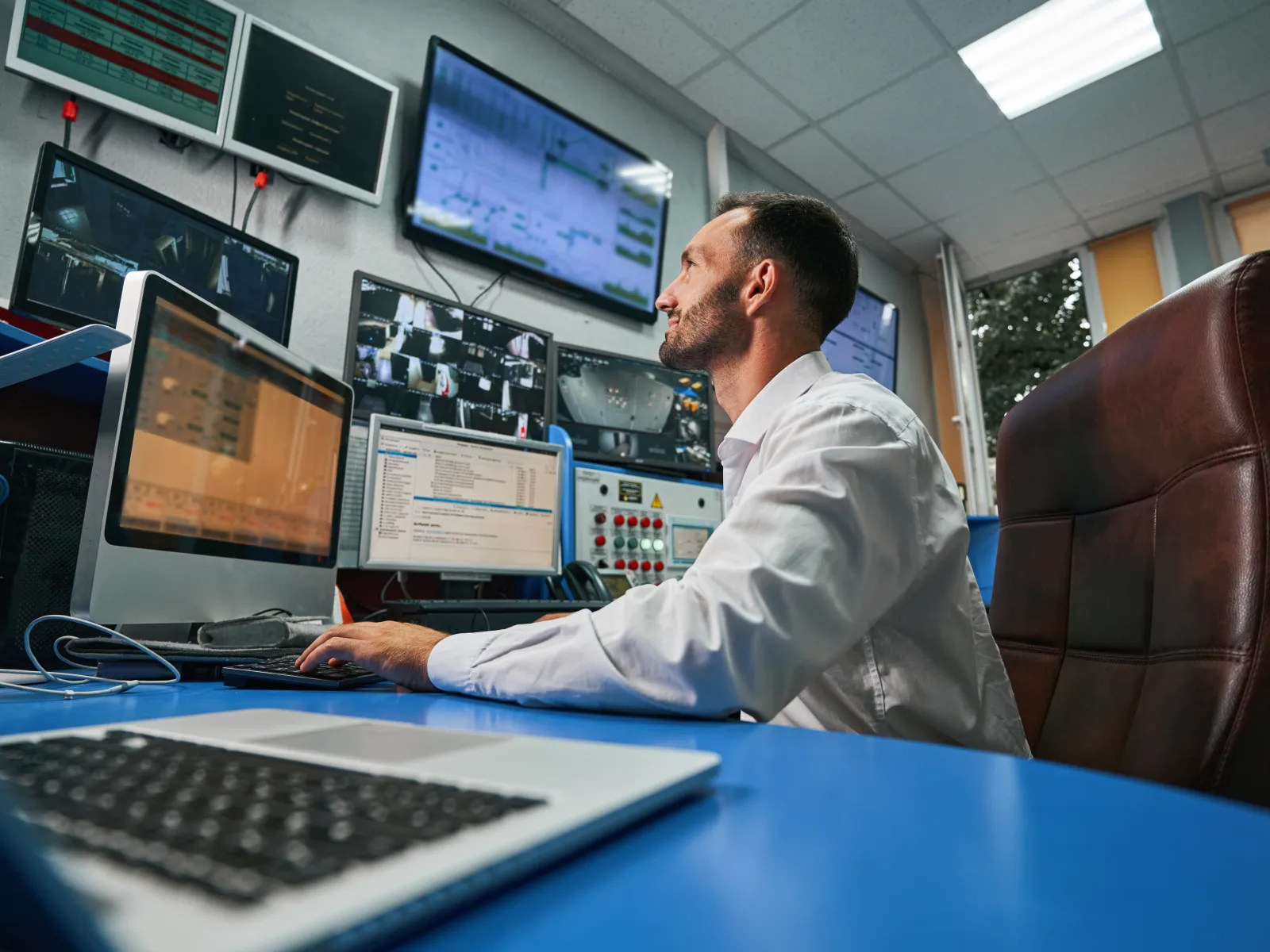 a man sitting at a desk with multiple monitors