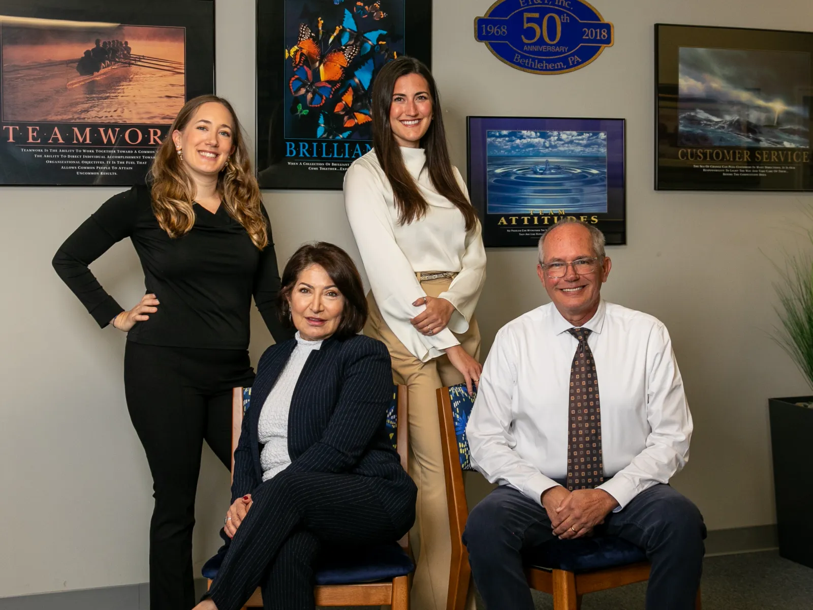 Professional group portrait of four diverse business colleagues in an office with motivational posters on the wall.