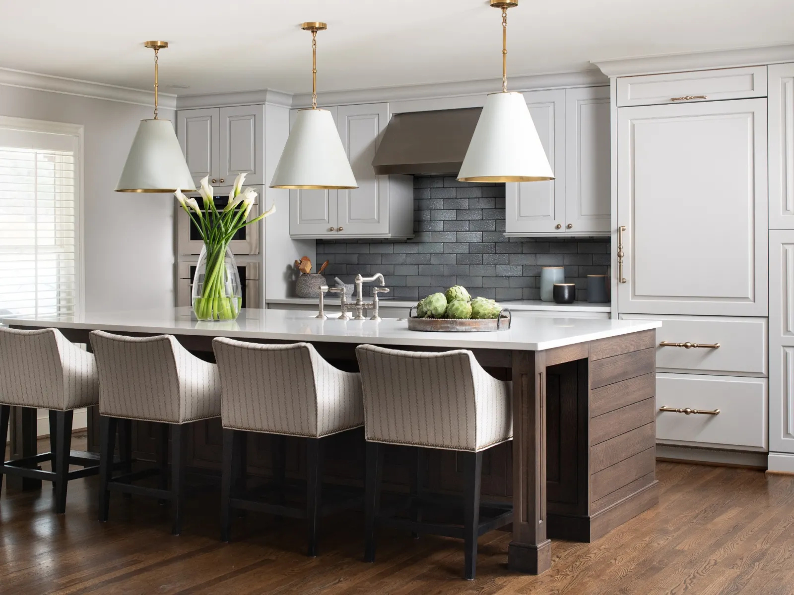 Modern kitchen featuring an island with bar stools, stylish pendant lights, and elegant cabinetry.