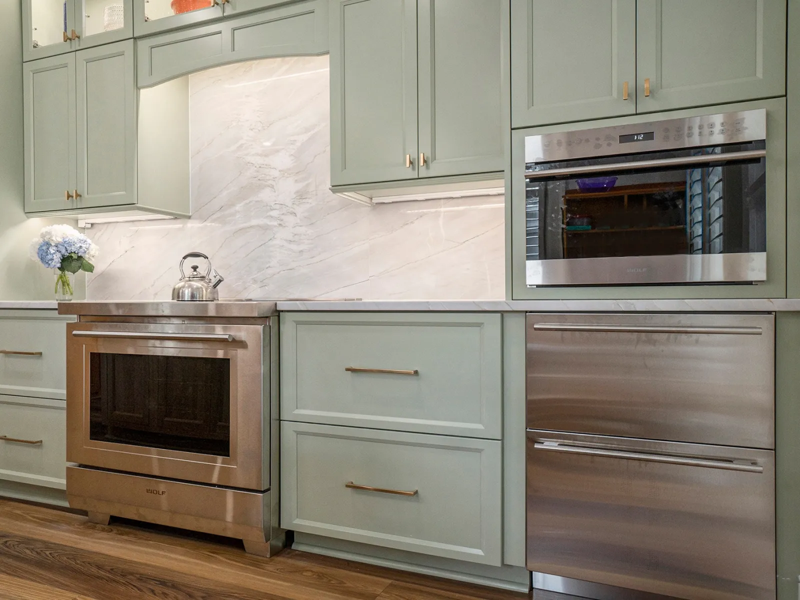 Modern kitchen with green cabinetry, stainless steel appliances, and sleek countertop design.