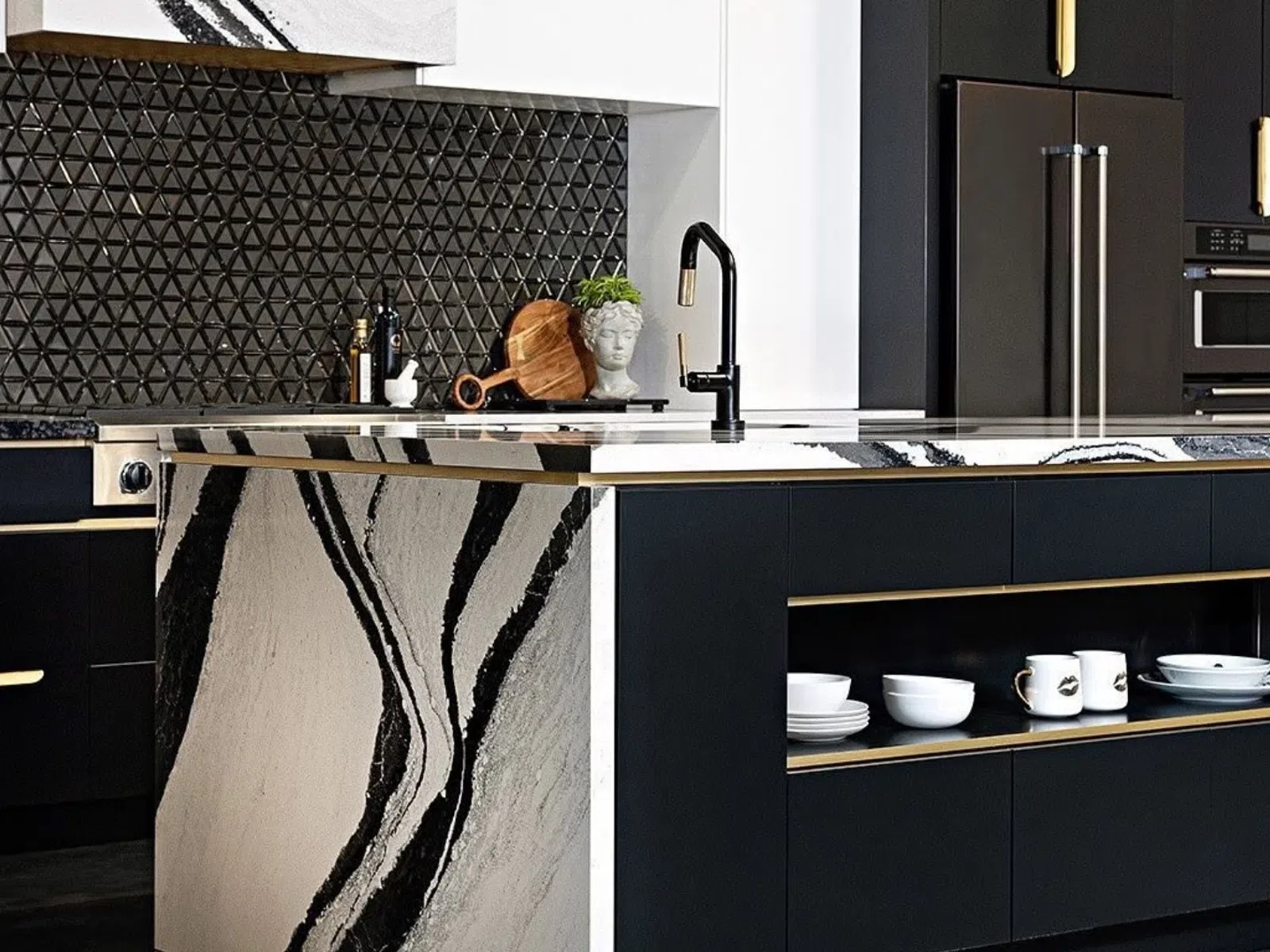 Modern kitchen with black cabinetry, marble island featuring bold veining, and geometric textured backsplash