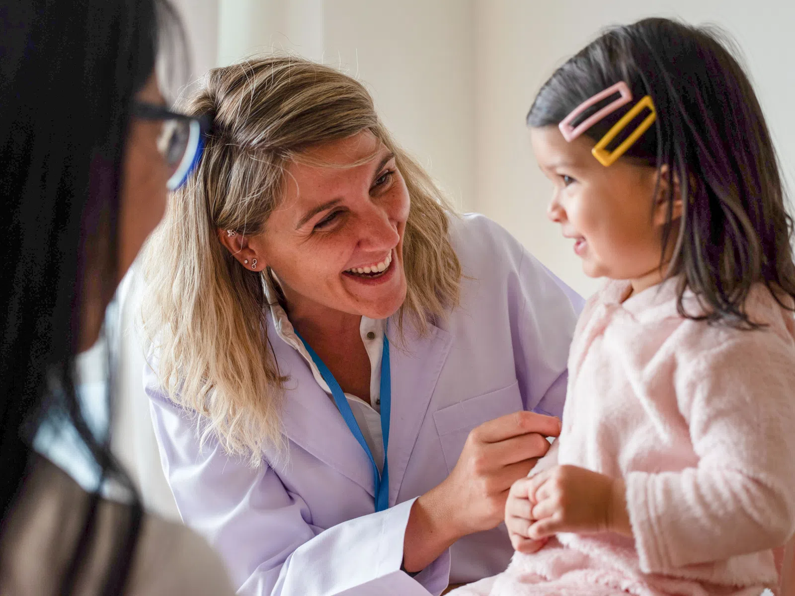 Smiling female doctor interacts with young girl patient during a friendly medical check-up in clinic.