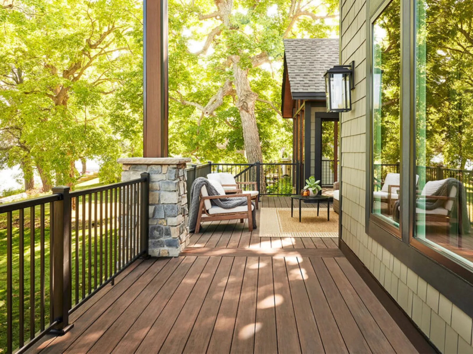 a deck with a chair and a table and a railing with trees in the background
