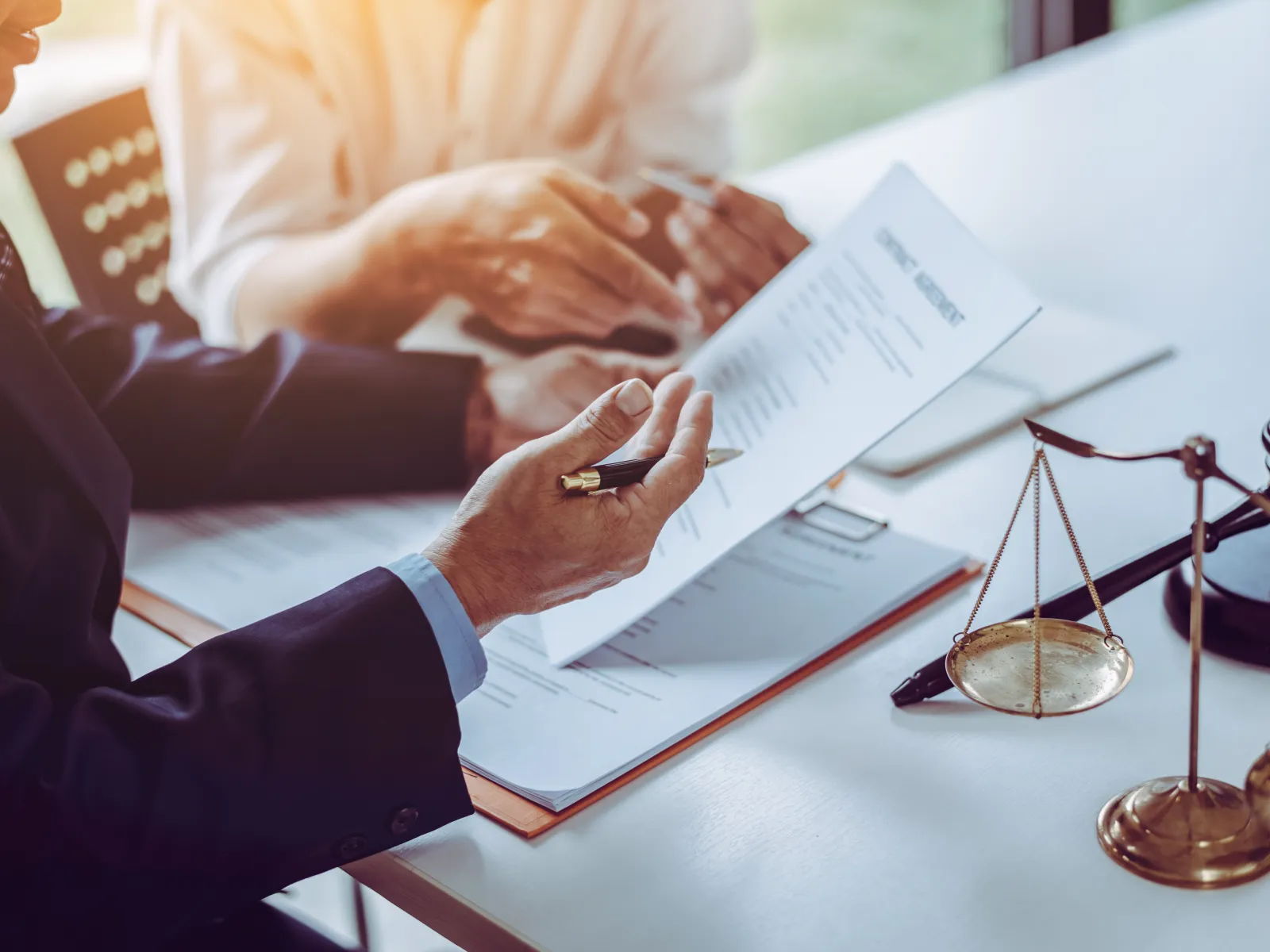Lawyer discussing legal contracts with client at desk featuring scales of justice and gavel