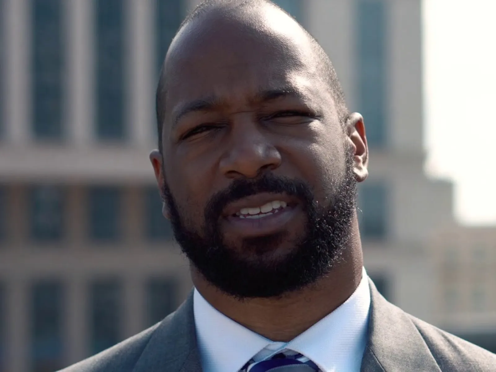 Close-up of a professional man in a suit and tie outdoors with city buildings blurred in the background
