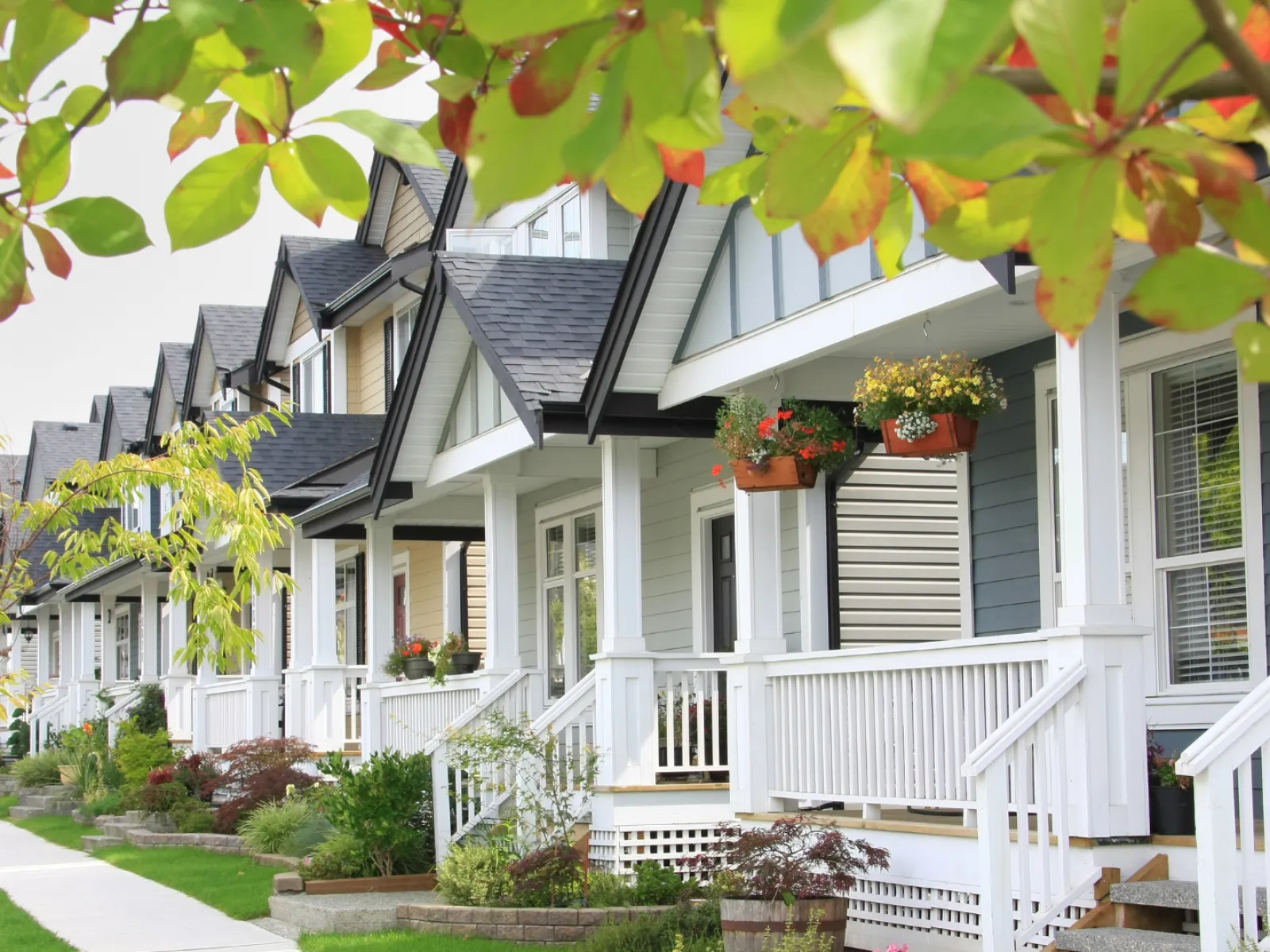 Row of charming houses with porches and seasonal foliage lining the walkway.
