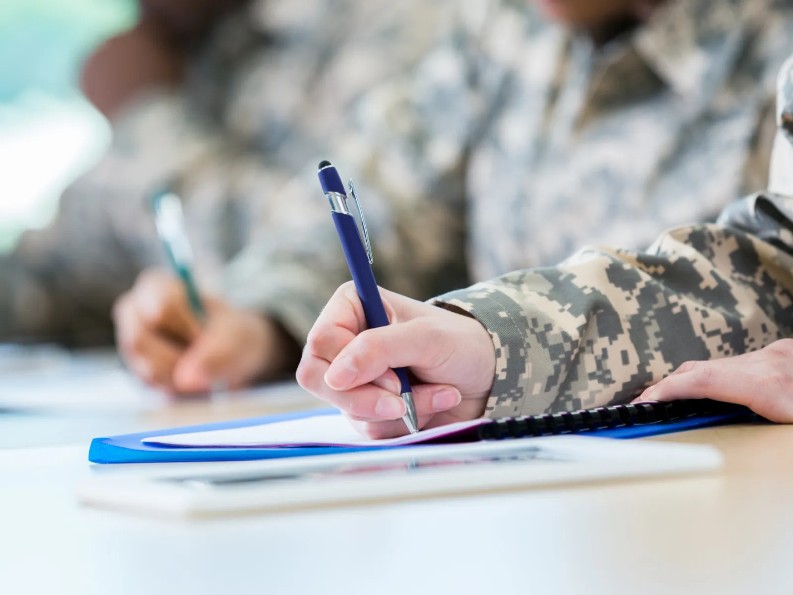 Military personnel in uniforms taking notes during a training session or meeting.