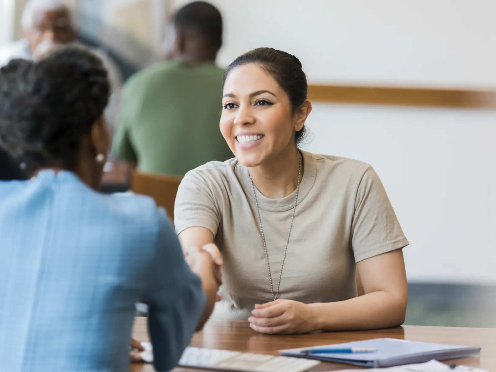 Two women shaking hands in a warm and professional setting, showing collaboration and connection.