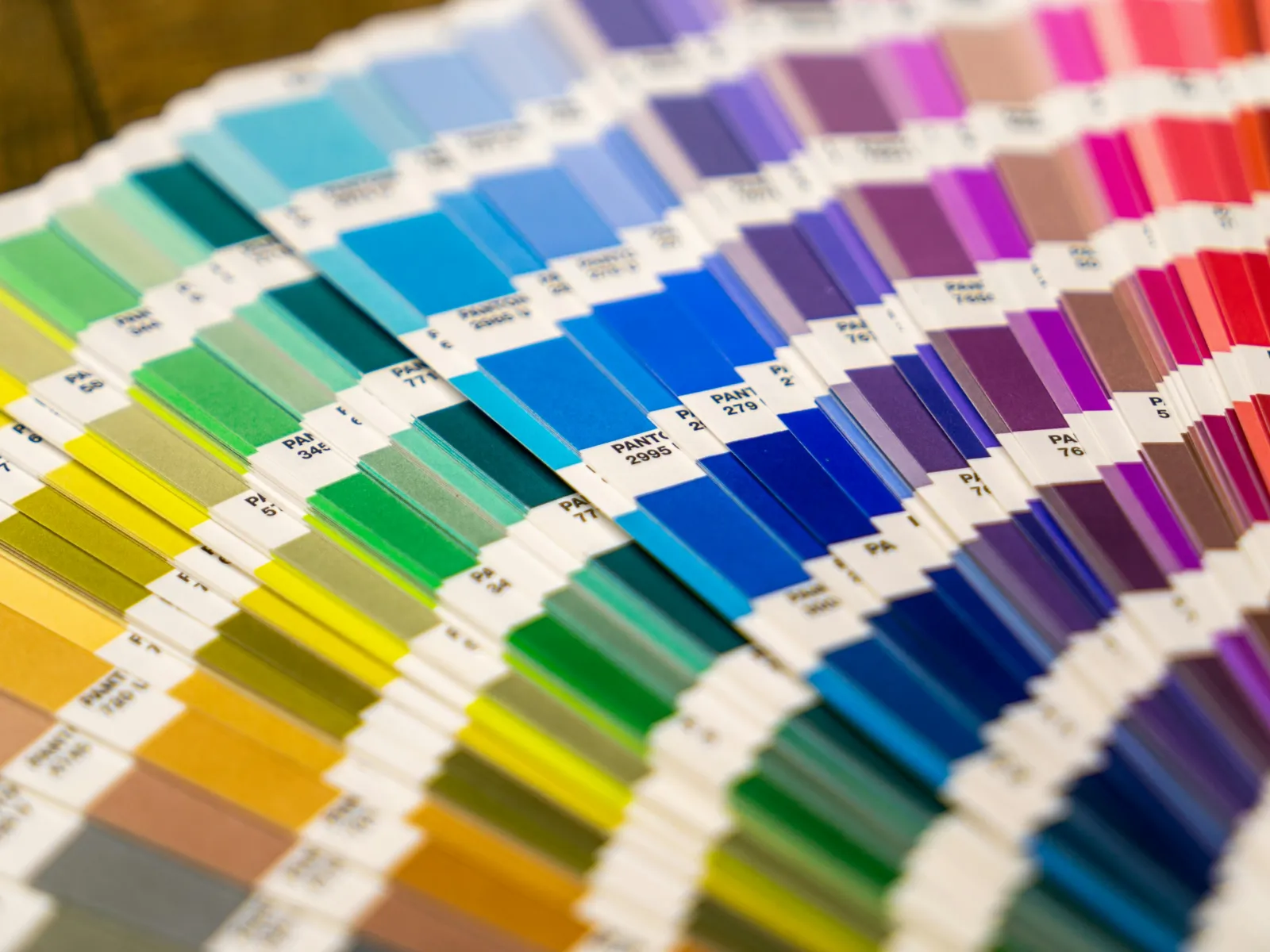 Fan of Pantone color swatches displaying a gradient from yellows to reds, blues, and greens for design use.