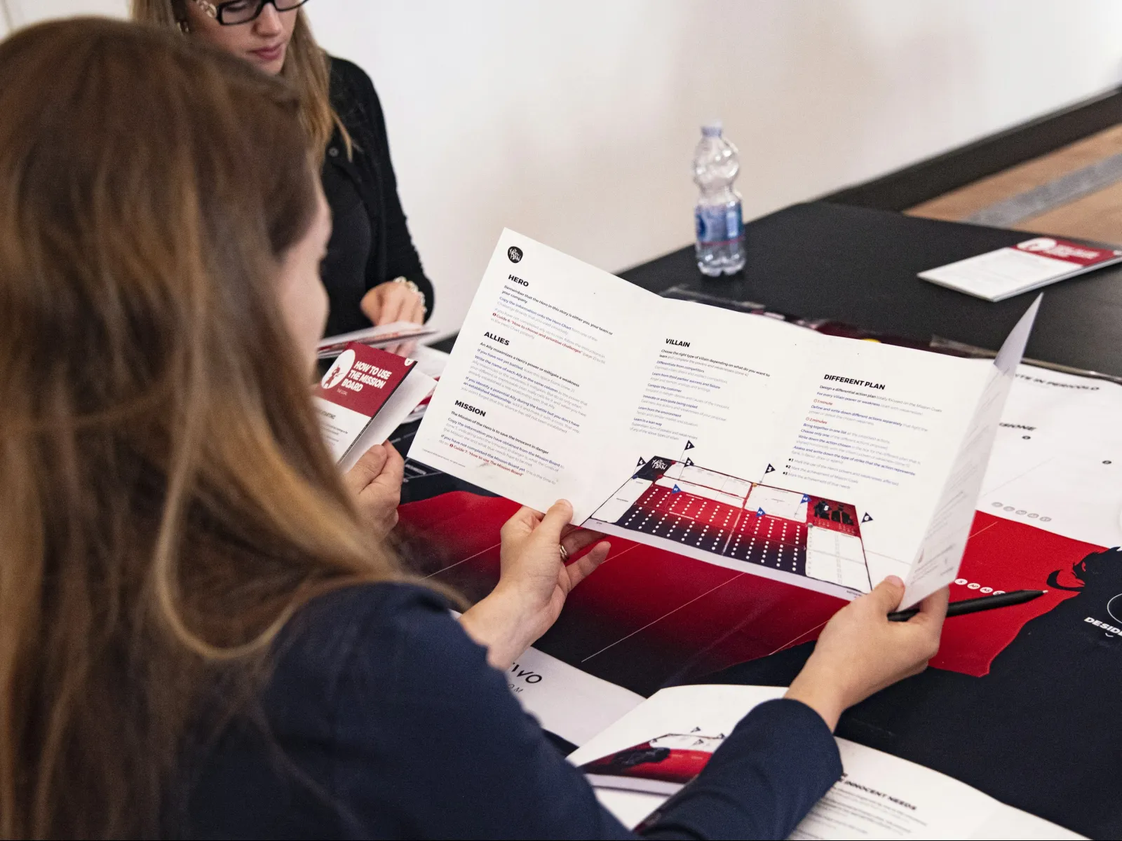 a group of people sitting at a table with papers and pens