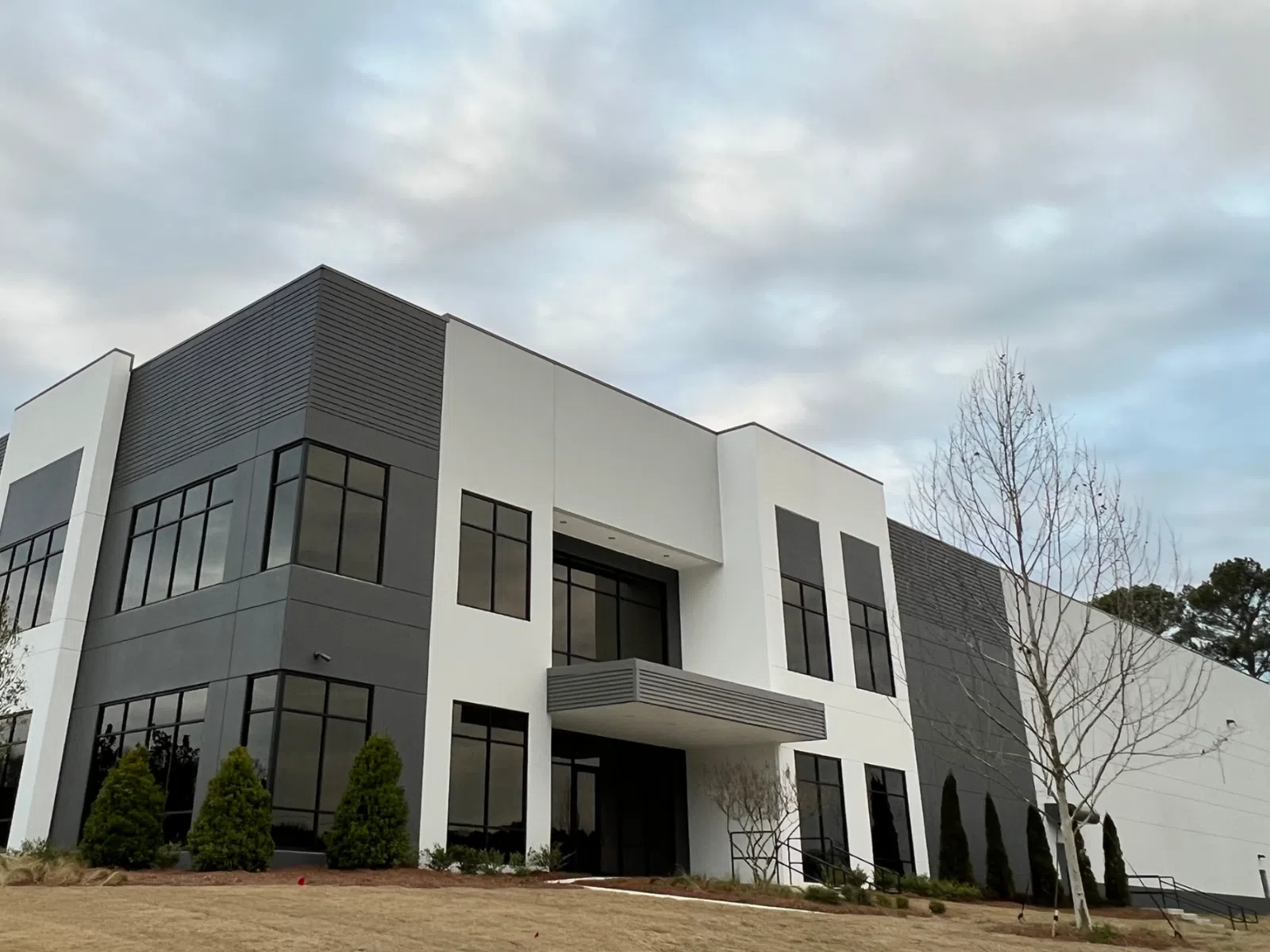 Modern industrial warehouse building with large windows and landscaped exterior.