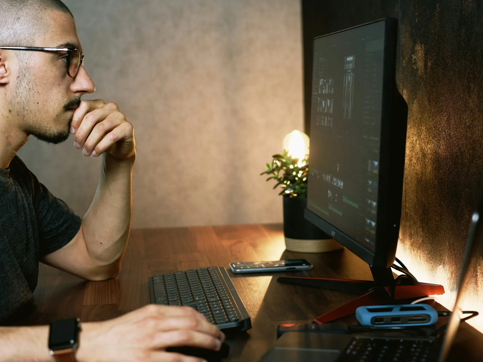 a man sitting at a desk with a computer and a phone