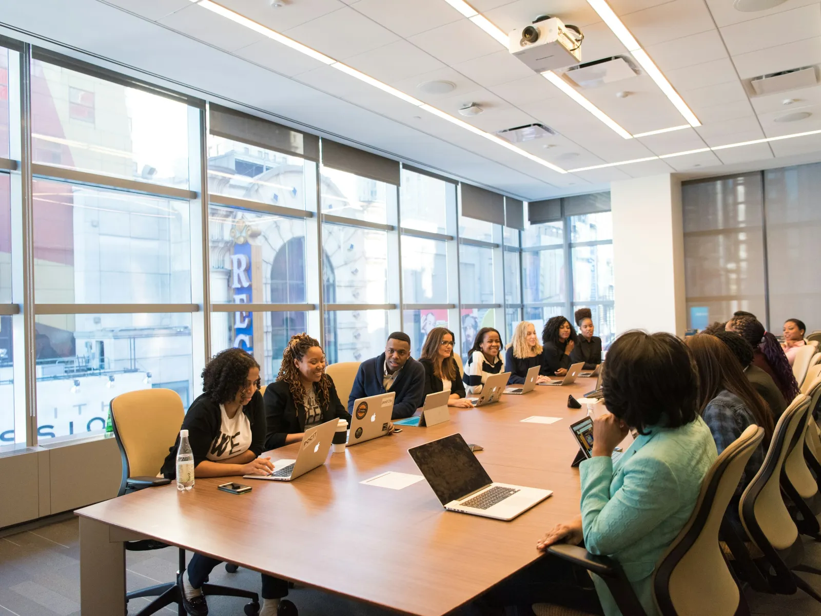 People of diverse backgrounds having a meeting around a large conference table with laptops in a modern office.