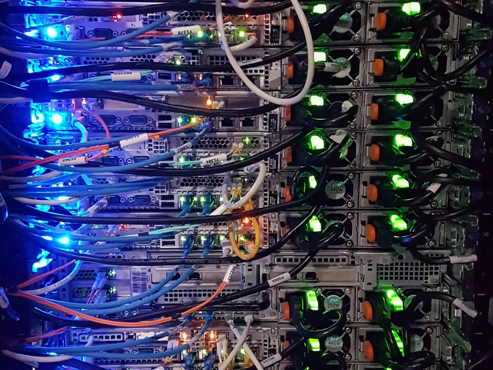 Data center server rack with connected cables and glowing blue and green indicator lights in a network hub.
