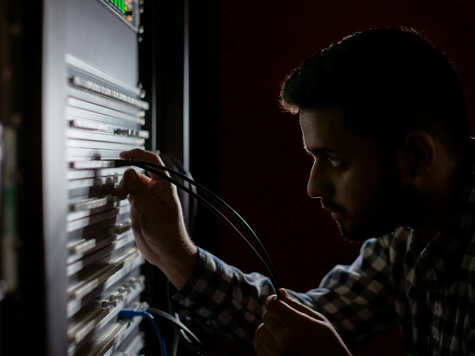 A technician connecting cables in a server rack, focusing on network equipment and technology.