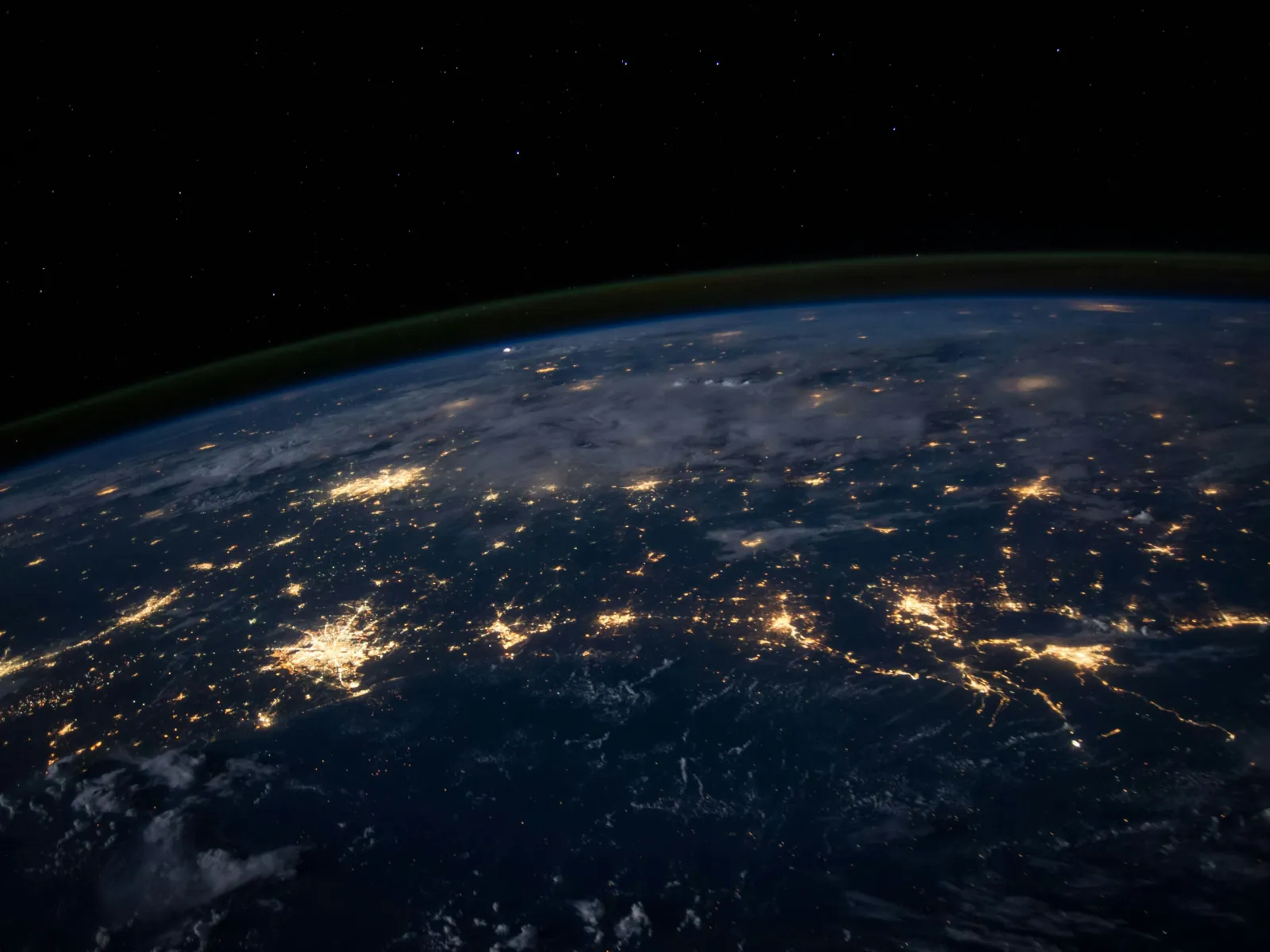 A stunning view of Earth at night showcasing city lights and natural landscapes from space.