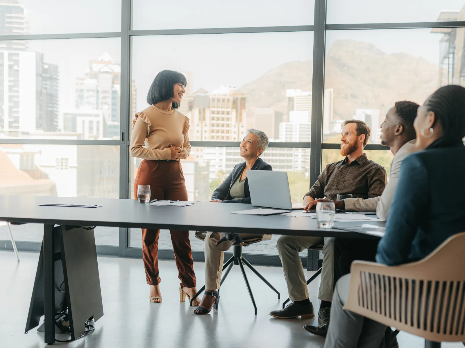 Customer service team working at computers wearing headsets in a bright modern office with large windows.