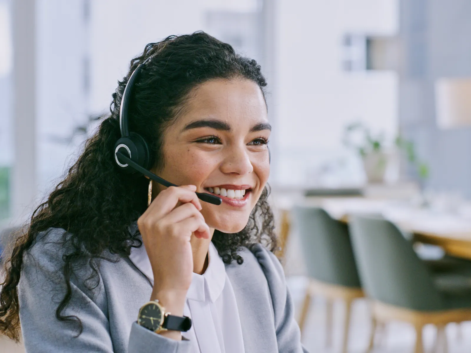 Smiling female customer service agent wearing headset working in modern office environment.