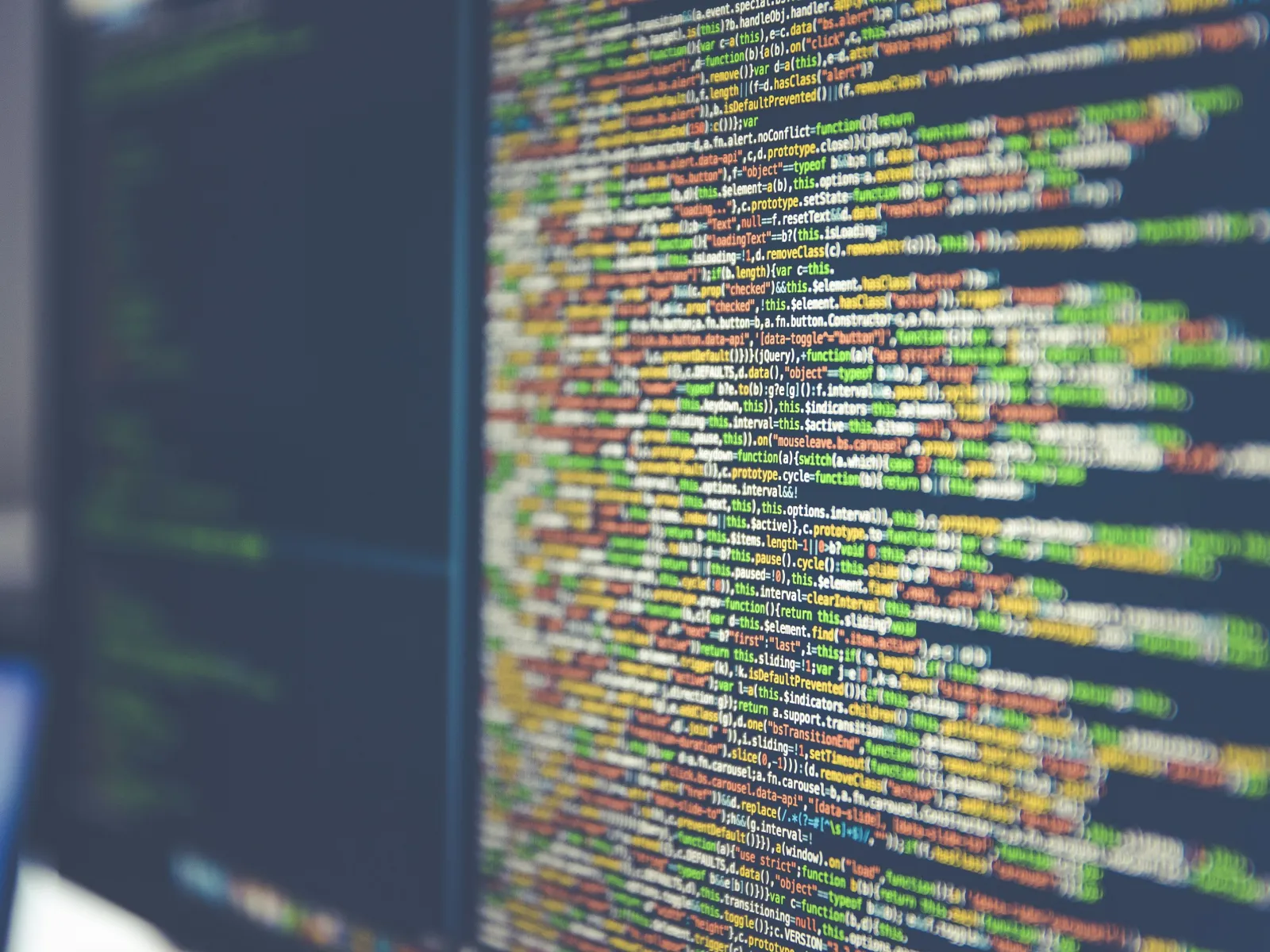 Blurred close-up of colorful programming code on a computer screen in a software development environment.