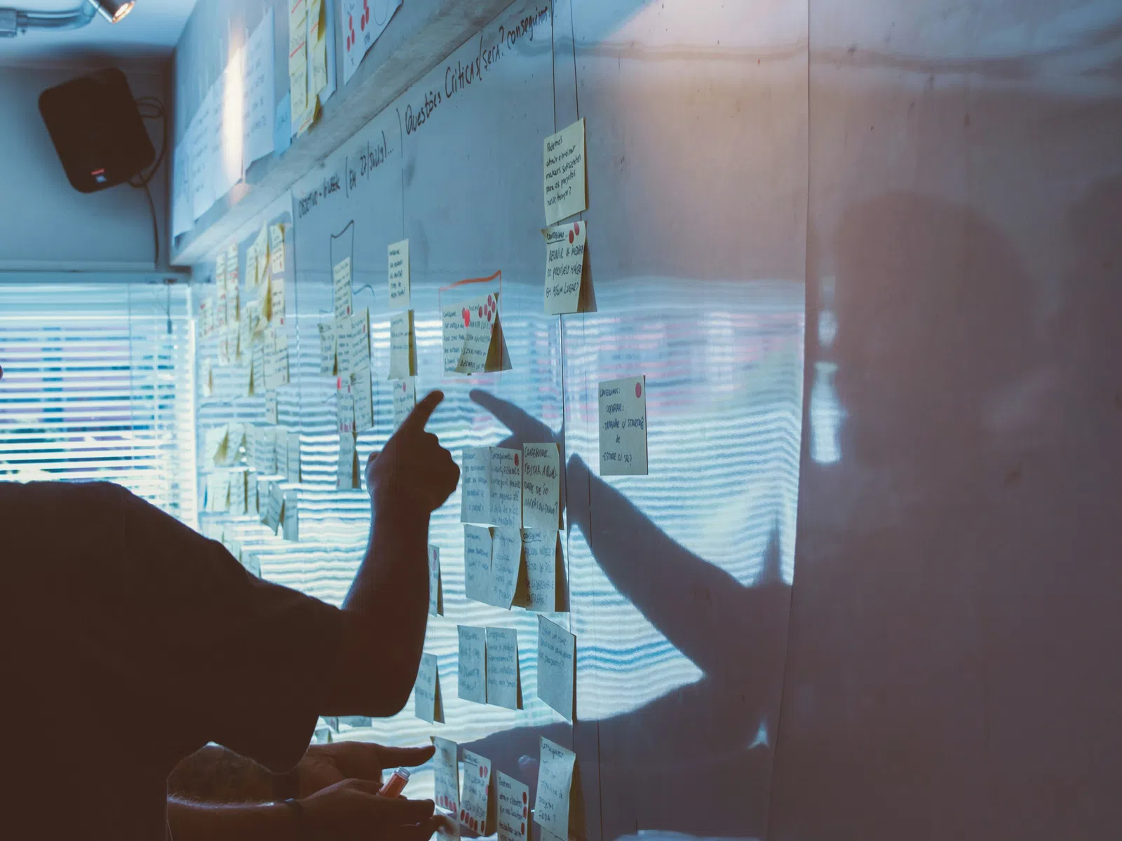 Person pointing at sticky notes with handwritten ideas on a whiteboard in a brainstorming session