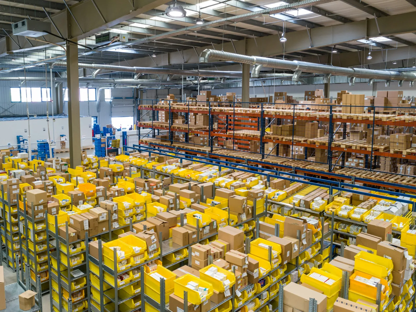 Large warehouse interior with rows of shelves filled with yellow and brown shipping boxes and packages.