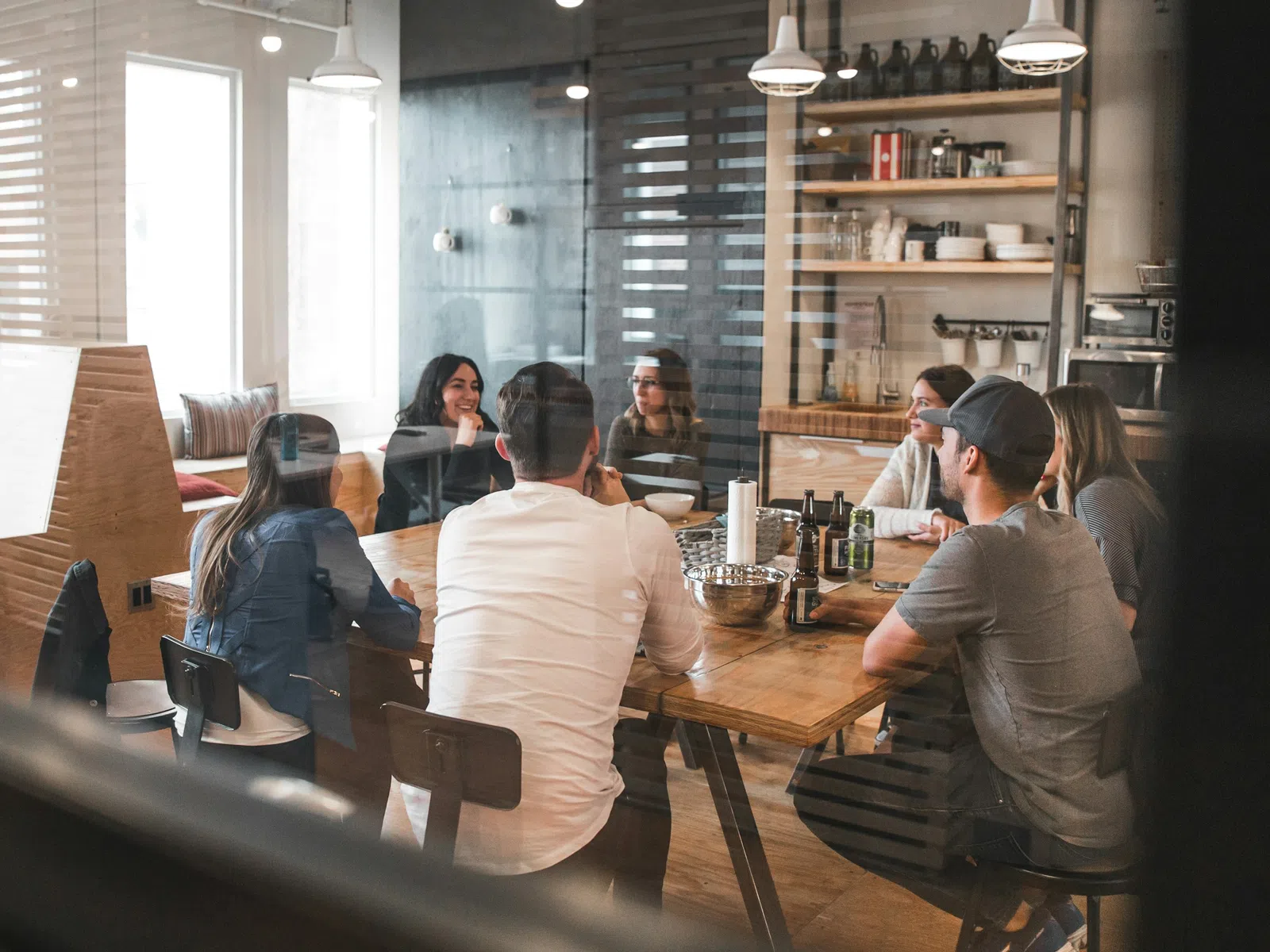Group of young professionals having a meeting around a wooden table in a modern office space.